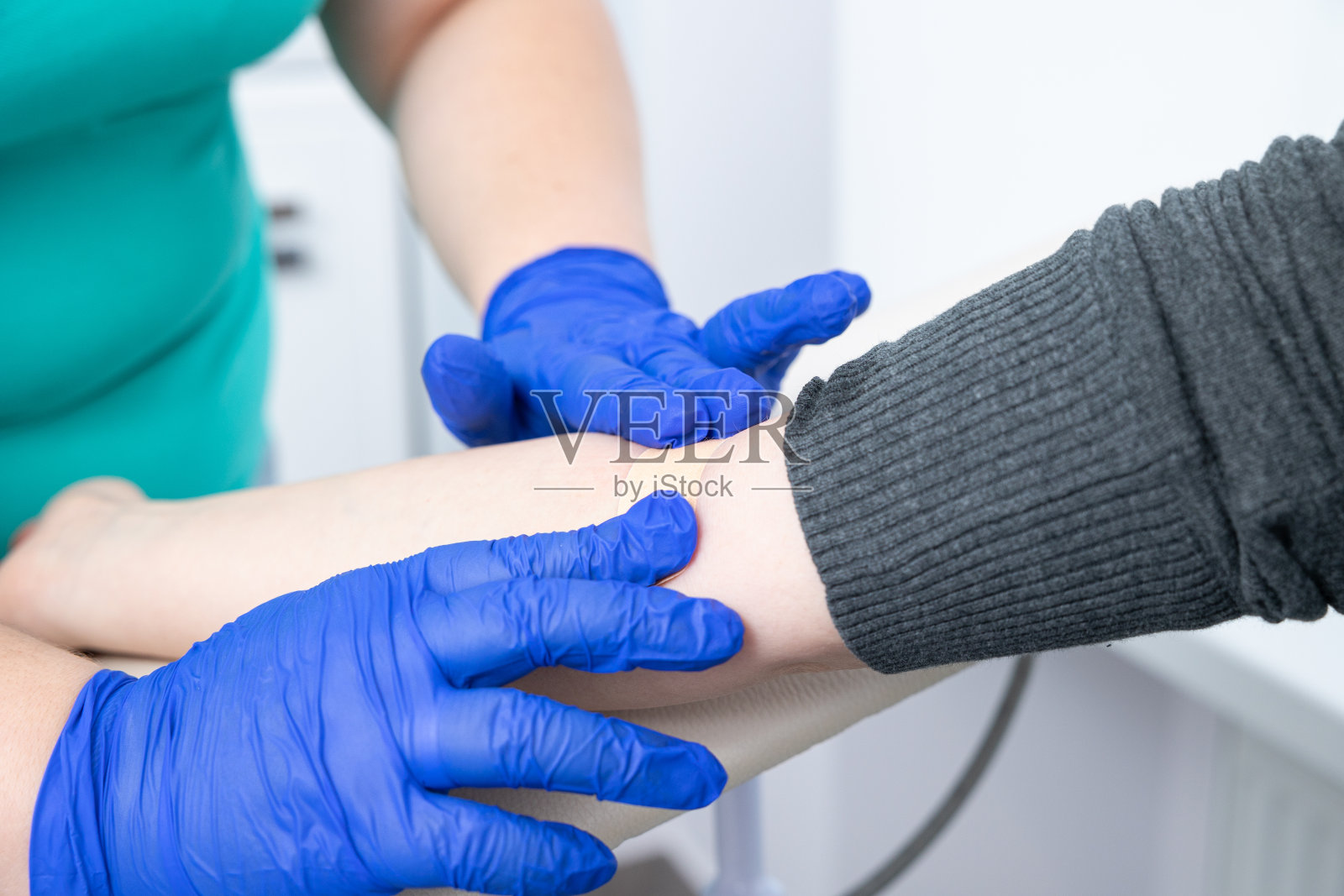 护士从病人的静脉取血后，把一块胶布固定在病人的手臂上。照片摄影图片