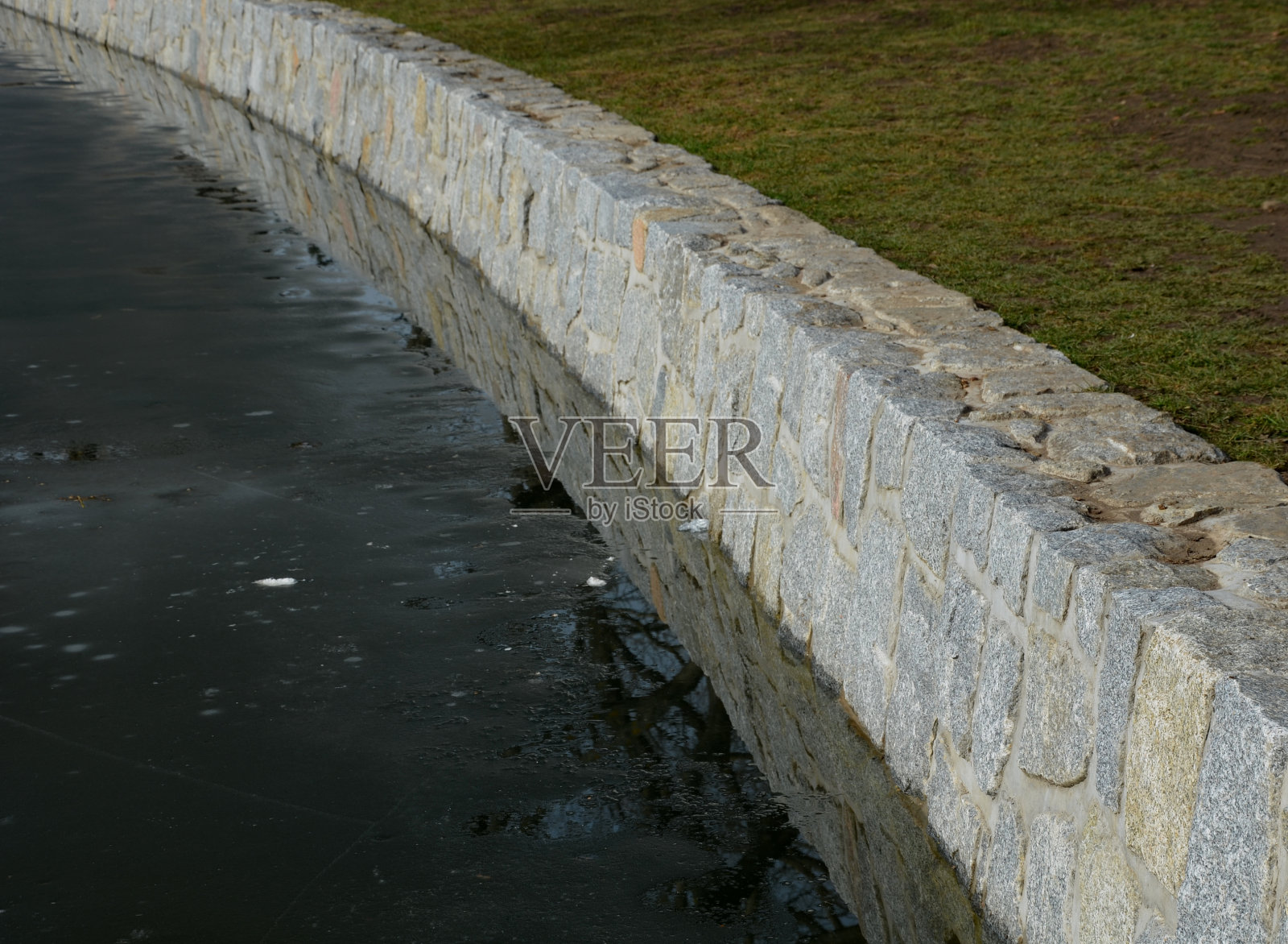 水库或河塘码头的石头挡土墙，加固的花岗岩墙。在大坝上有一个泄洪闸，用来把水泄入河流。覆盖板照片摄影图片