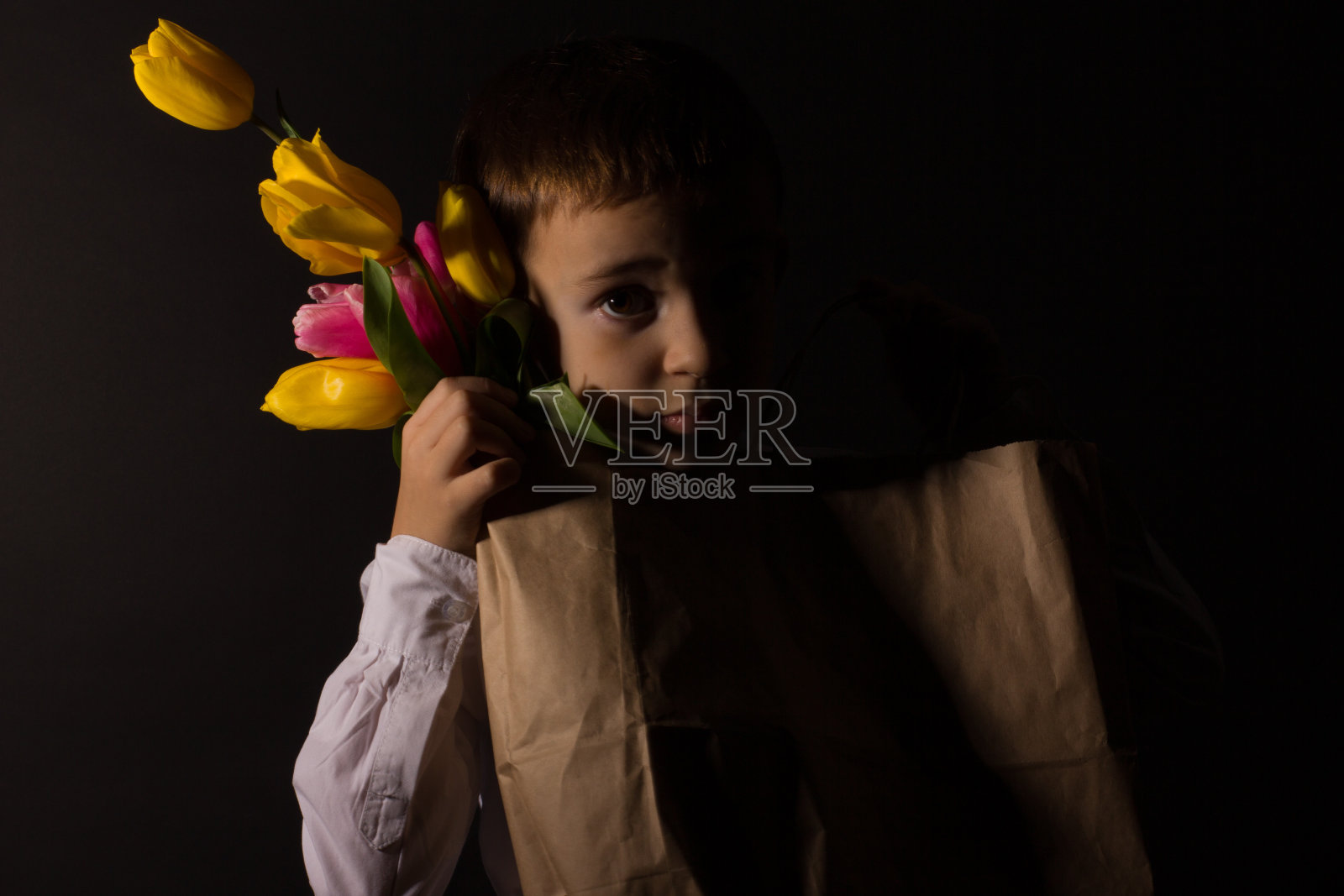 那个白癜风的男孩穿着白色衬衫，打着蝴蝶结，背景是黑色的Studio照片摄影图片