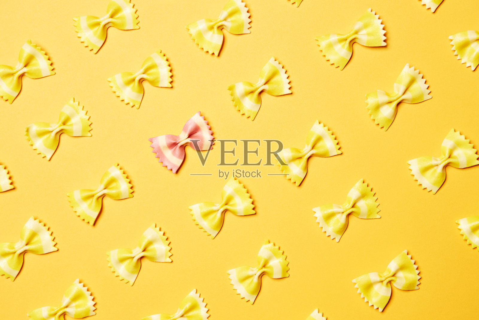 粉红色的蝴蝶结，蝶形的意大利面片站在黄色的片在黄色的背景照片摄影图片