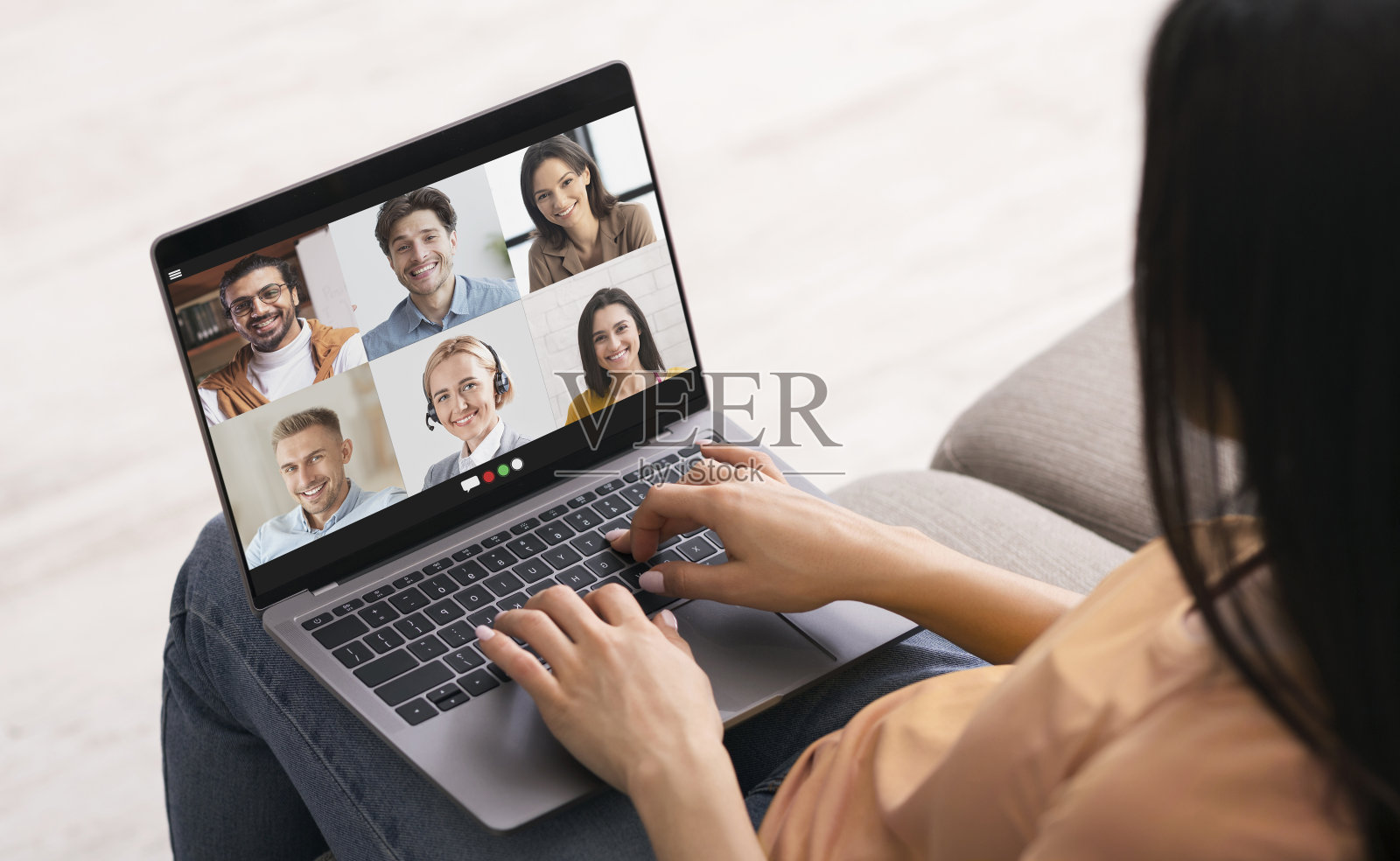 距离的沟通。一位年轻的女士在家里办公室用笔记本电脑和她的同事进行在线小组会议照片摄影图片