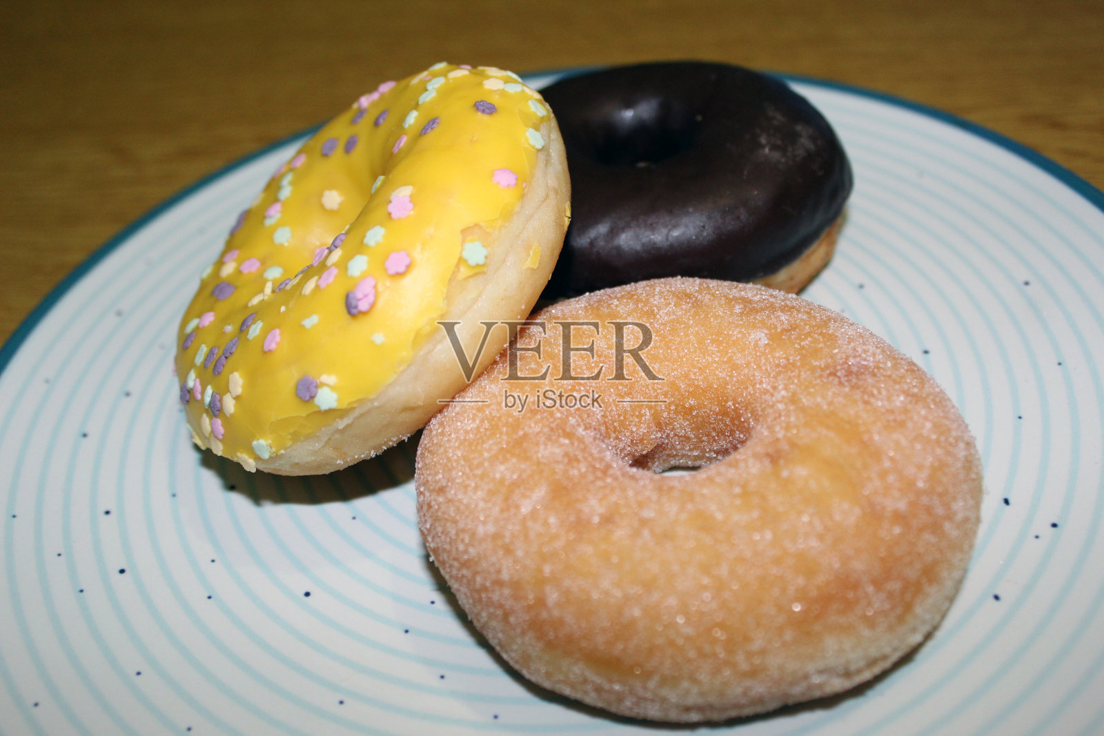 三个甜甜圈孤立在一个蓝色的圆盘子上照片摄影图片