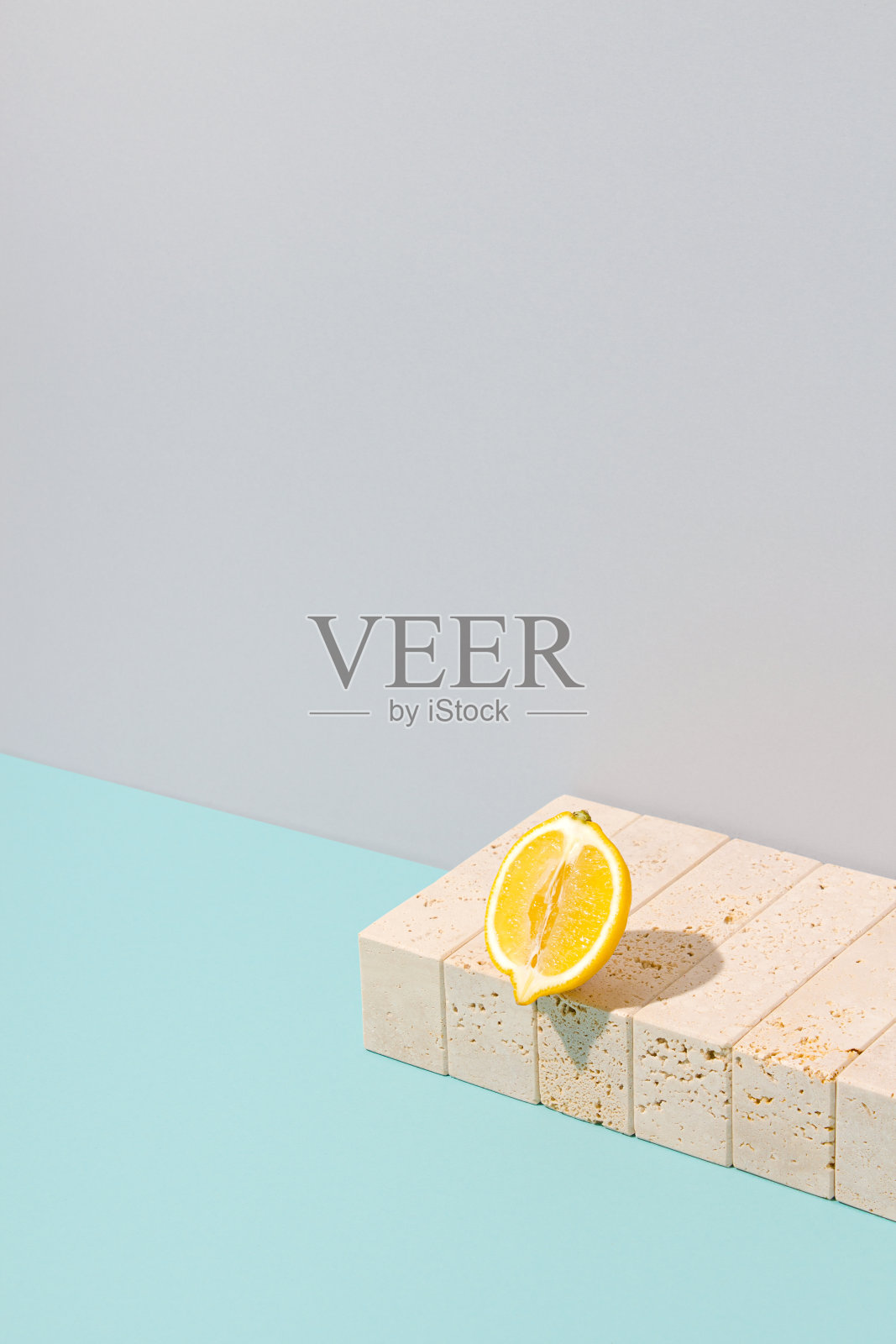 切片柠檬放在游泳池边上。黄色的夏季水果排列与青色和灰色的背景。超现实的大理石石材复古概念。阳光下柔和的彩色复古海滩场景。照片摄影图片