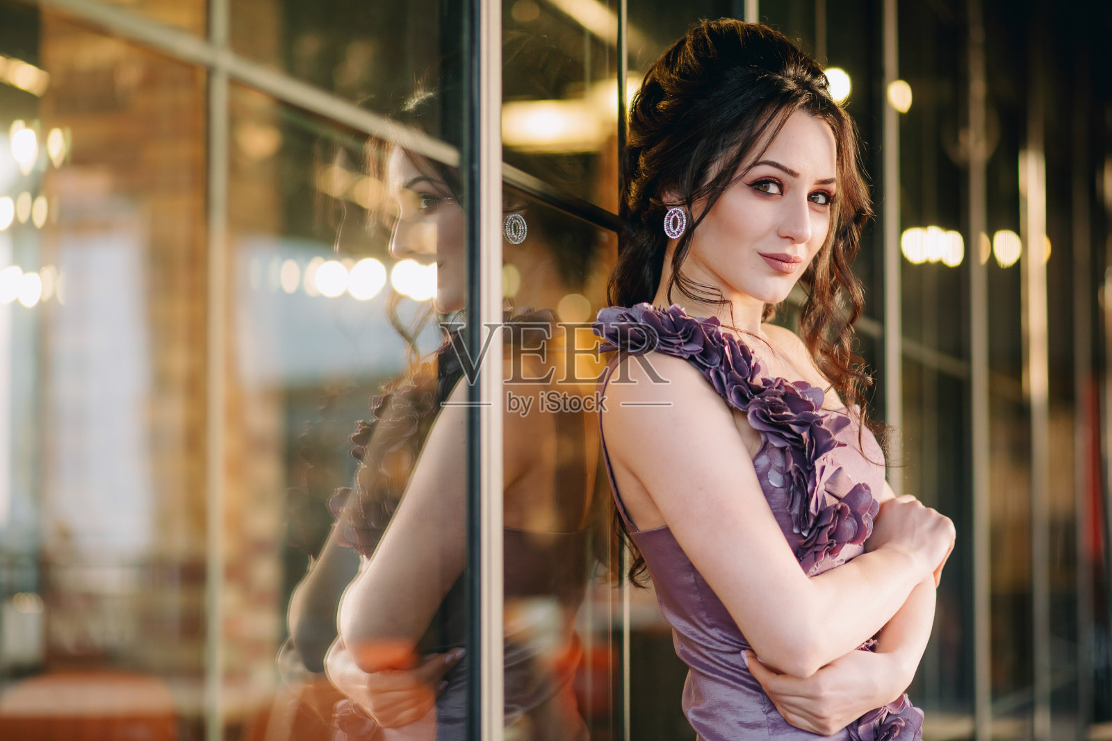 穿着紫色衣服的年轻女子靠在现代餐厅的滑动窗口上照片摄影图片