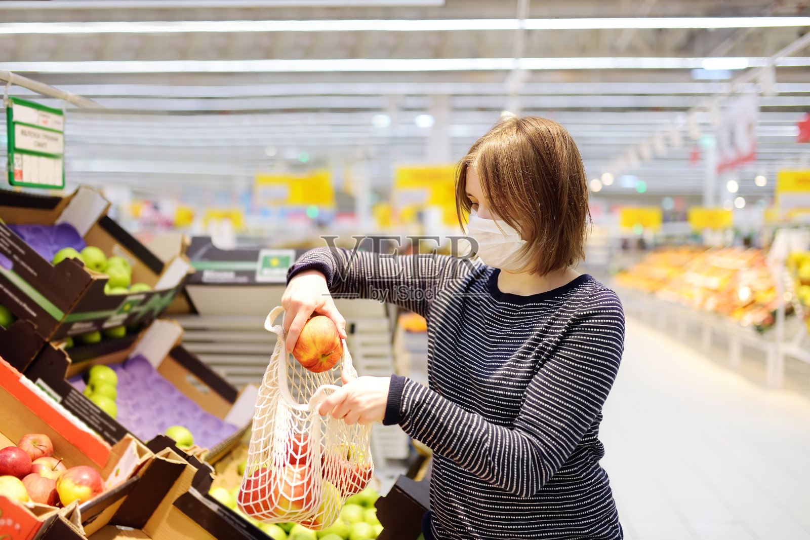 一名年轻女子在冠状病毒肺炎爆发期间戴着防护口罩在超市购物。照片摄影图片