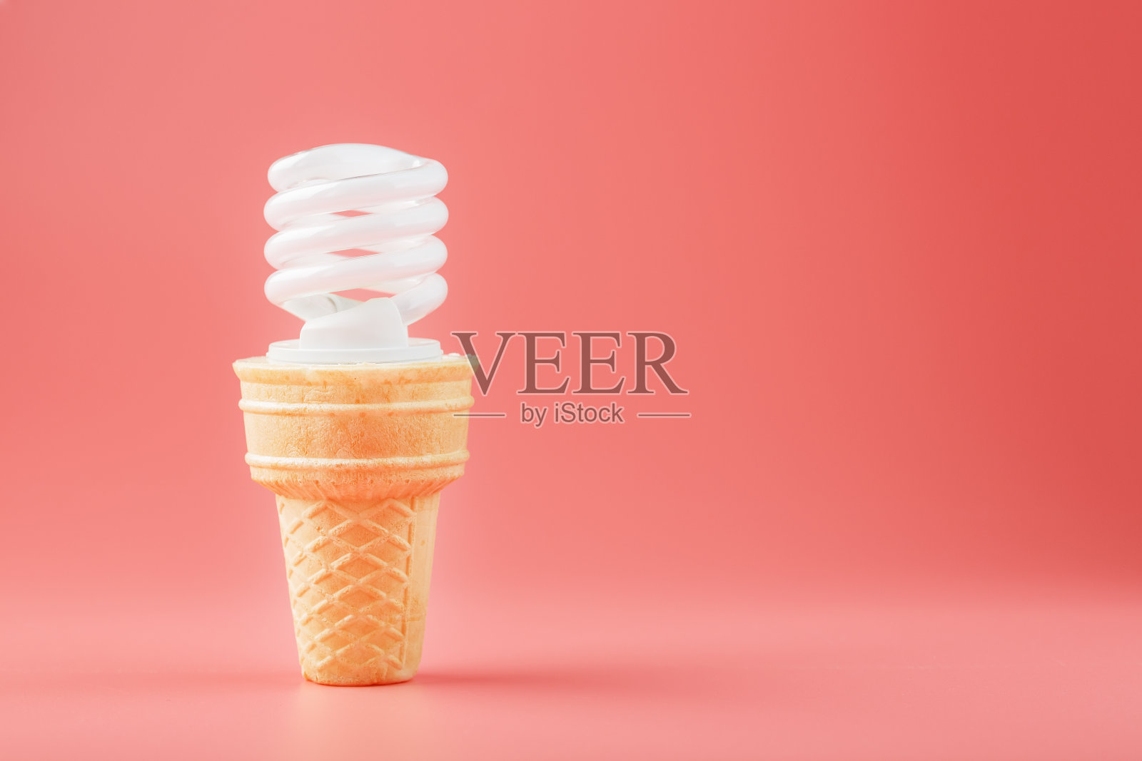 节能螺丝轻冰淇淋在华夫蛋筒在粉红色的背景。照片摄影图片