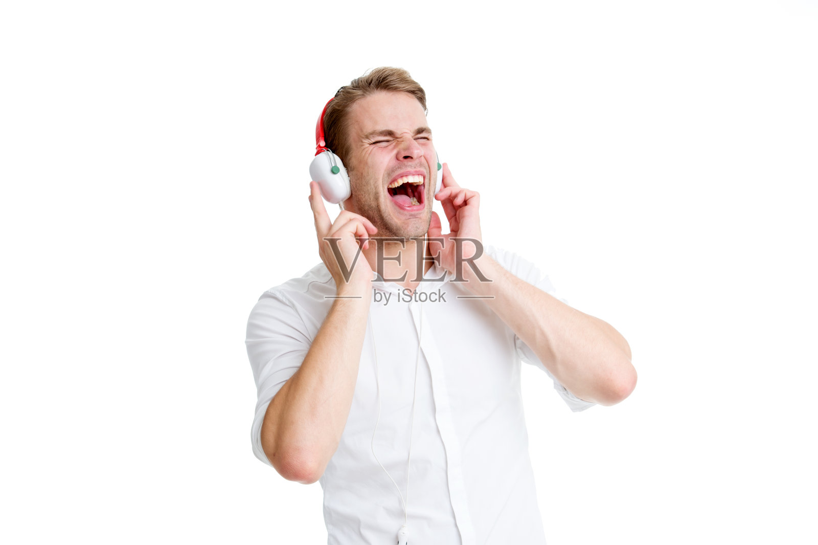 享受他最喜欢的歌曲。男人戴着耳机听着最喜欢的歌曲唱歌。戴耳机的人在听音乐。男人尖叫着脸享受着音乐孤立的白色背景照片摄影图片