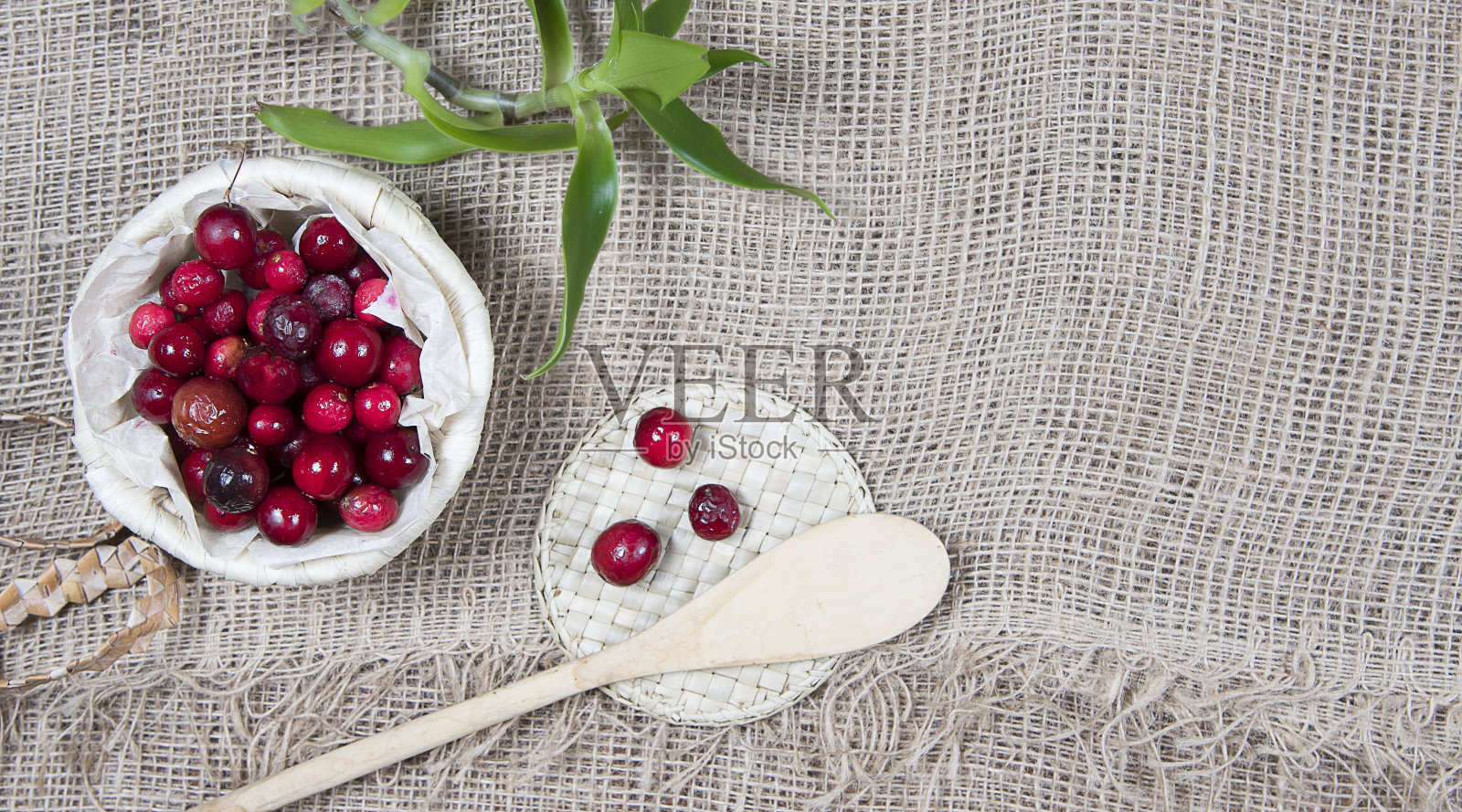 麻袋背景和木勺柳条篮子里的蔓越莓。Copyspace照片摄影图片