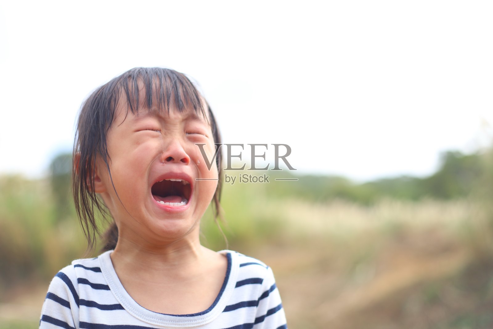 一个亚洲女孩在马厩里的马和驴里哭泣。照片摄影图片