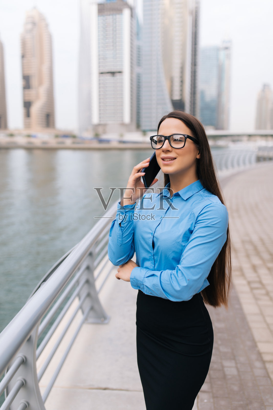 身穿西装的成功女经理在现代公司大楼外用手机交谈照片摄影图片