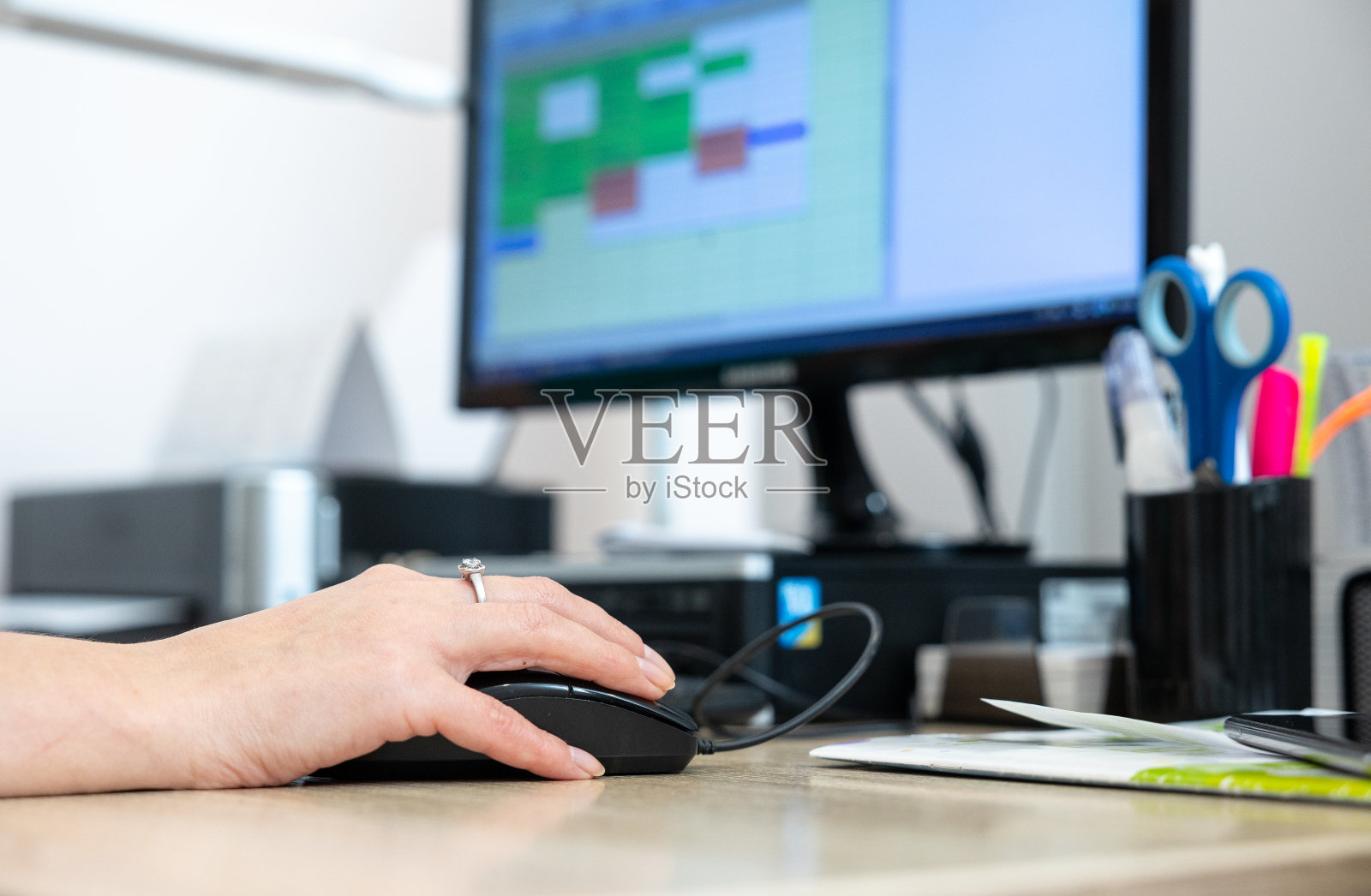 一个女性的手正在用一个固定的电脑鼠标。照片摄影图片