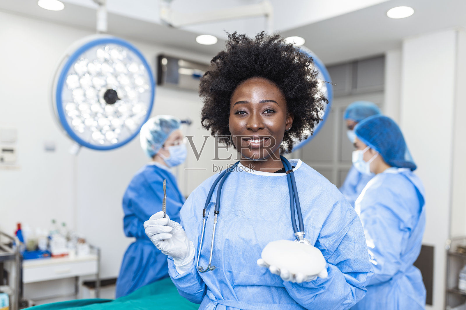 非裔美国整形外科医生在外科室内拿着硅胶乳房植入物。整容手术的概念照片摄影图片