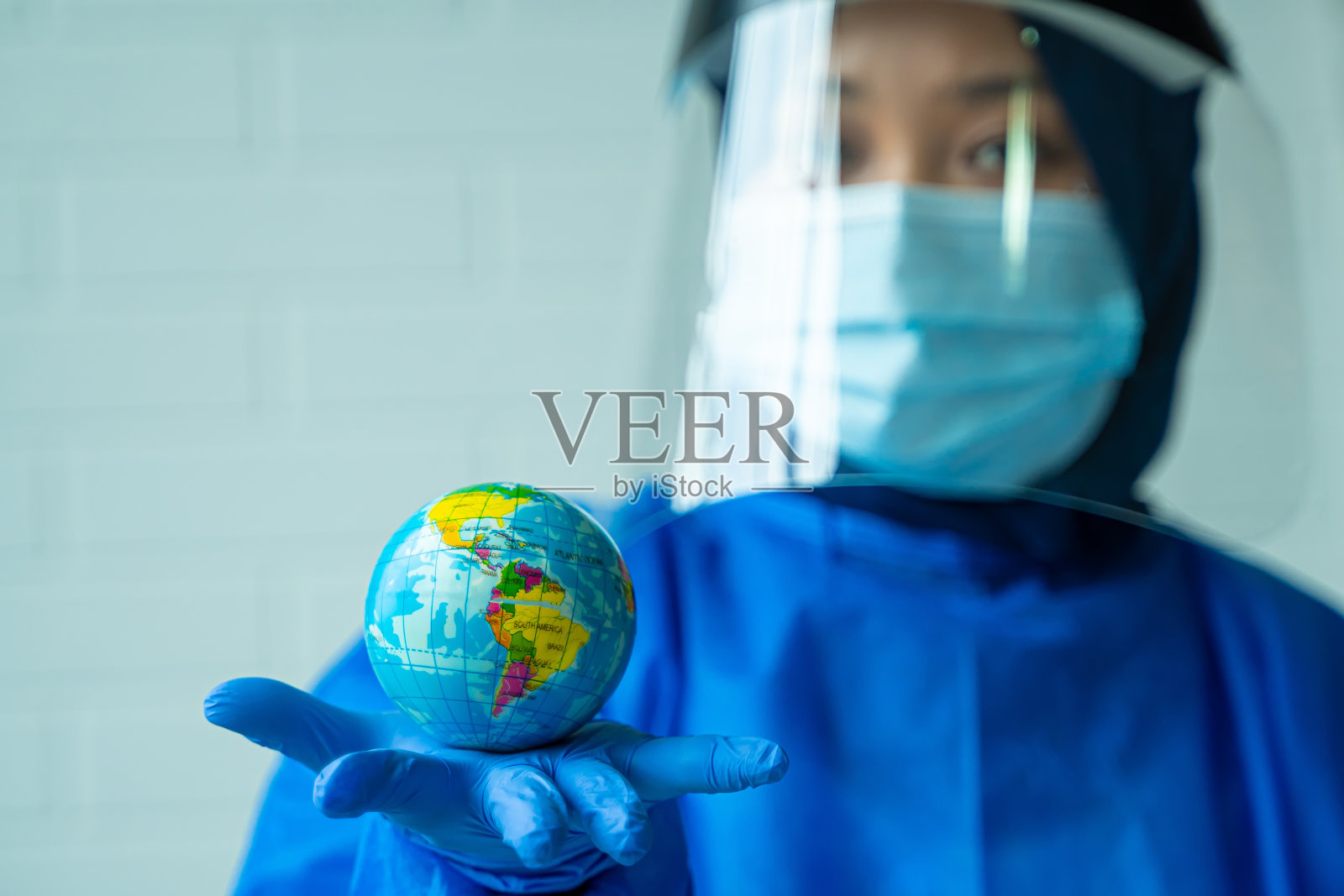 穿着个人防护装备，手持玻璃球的妇女照片摄影图片