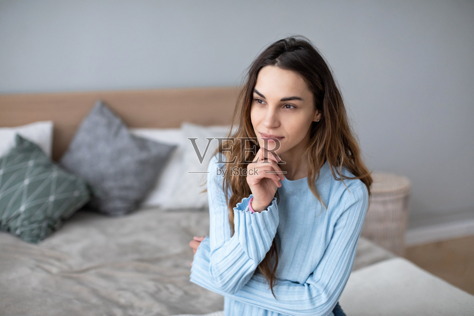 轻松微笑的女人坐在家里的沙发上。照片摄影图片