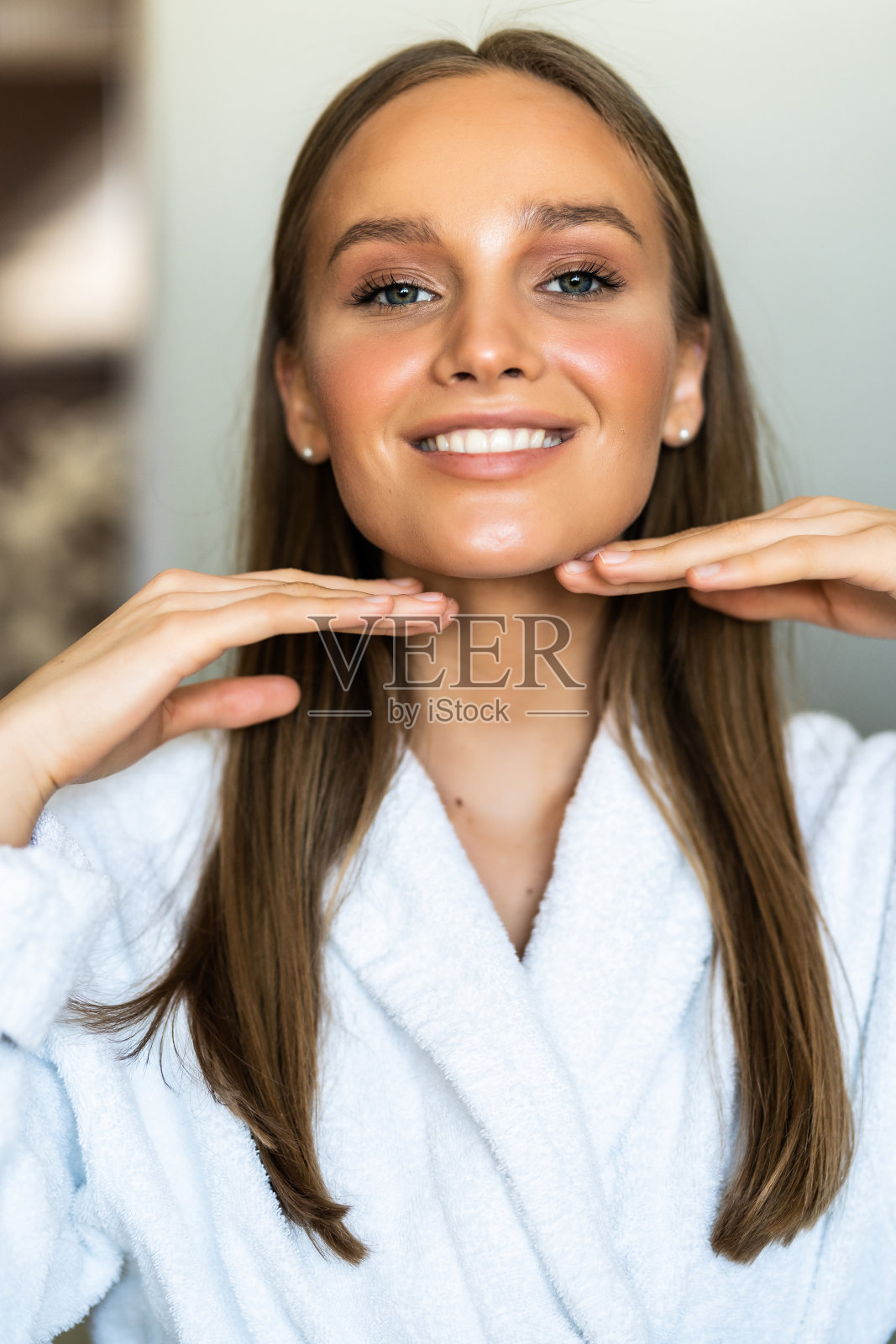 微笑的年轻女子触摸皮肤，在浴室照镜子照片摄影图片