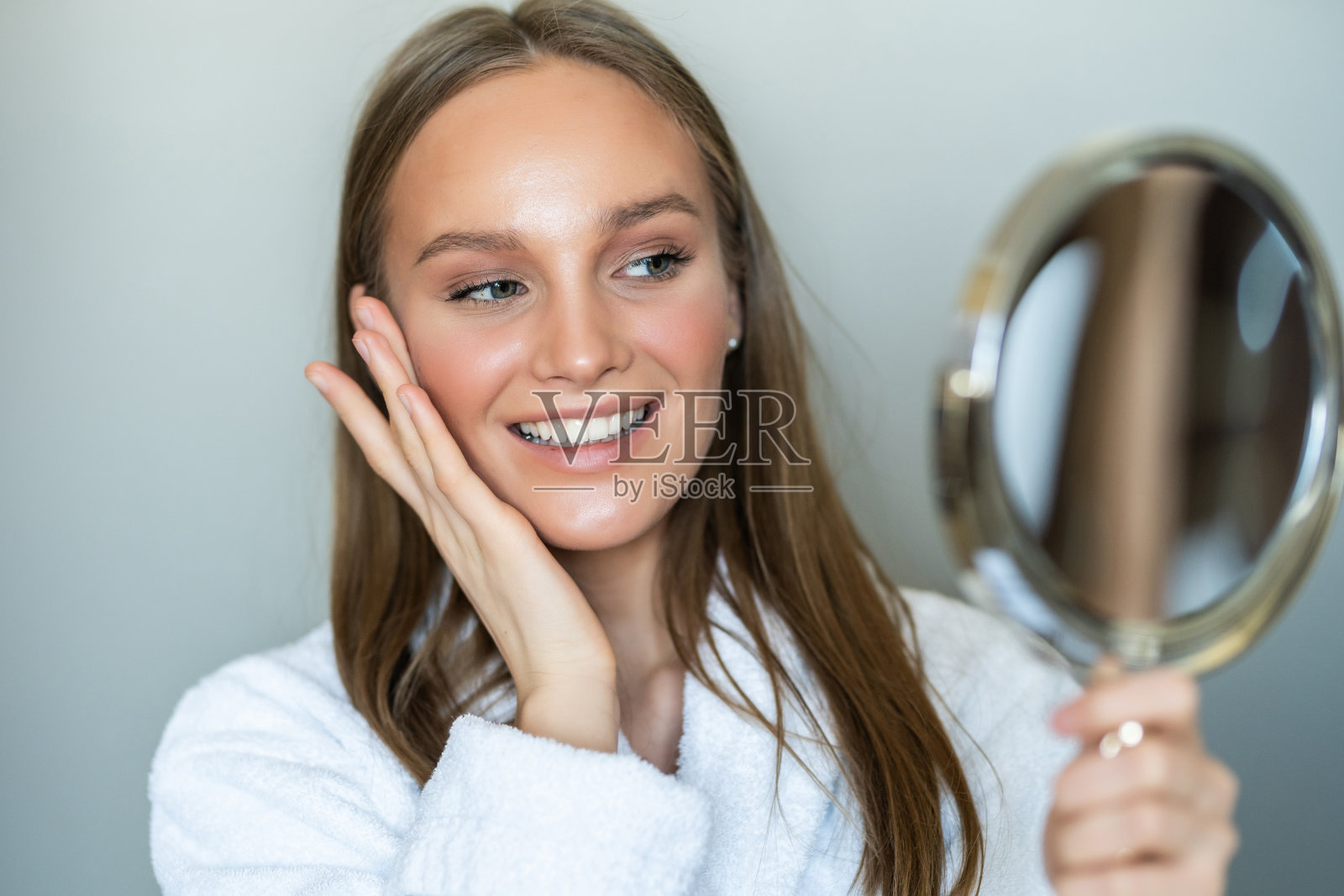 美丽的年轻女子与一个干净新鲜的皮肤接触与手脸颊照片摄影图片