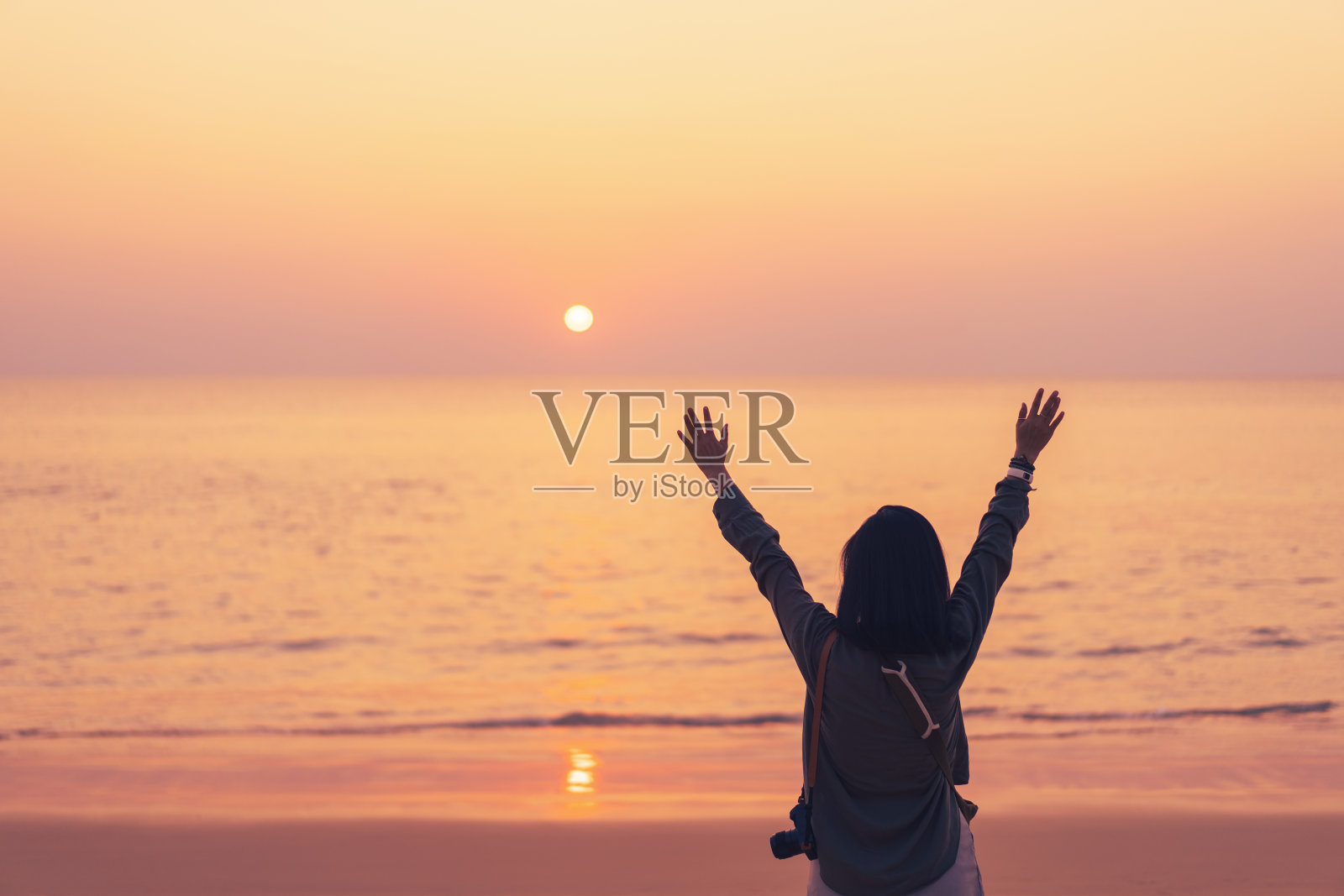 在海滩和岛屿背景的日落天空上复制女人举手的空间。照片摄影图片