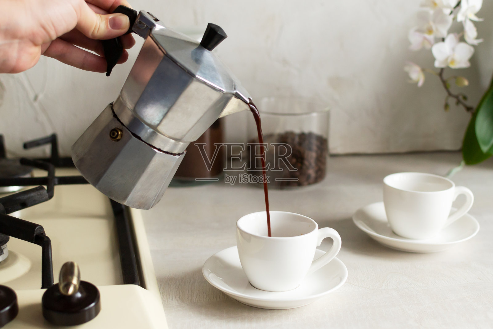 咖啡从间歇泉咖啡壶倒进浓缩咖啡杯。照片摄影图片