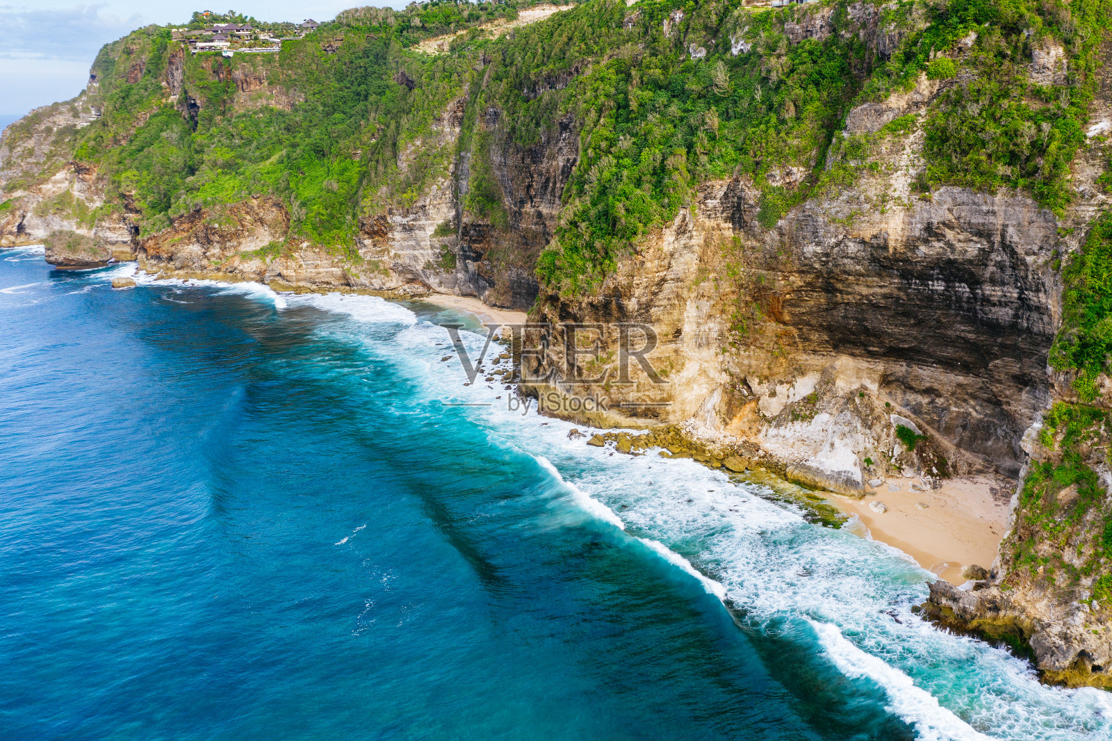 蓝色的海洋和被热带植物覆盖的悬崖。从上面看巴厘岛海岸。空中无人机拍摄。照片摄影图片