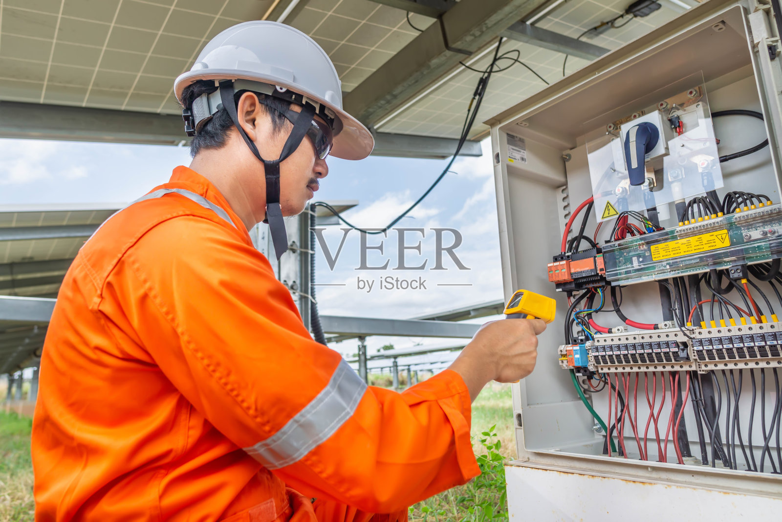 工程师使用热枪检查设备的温度，以确认系统工作正常。太阳能电池发电厂的专业工程师照片摄影图片