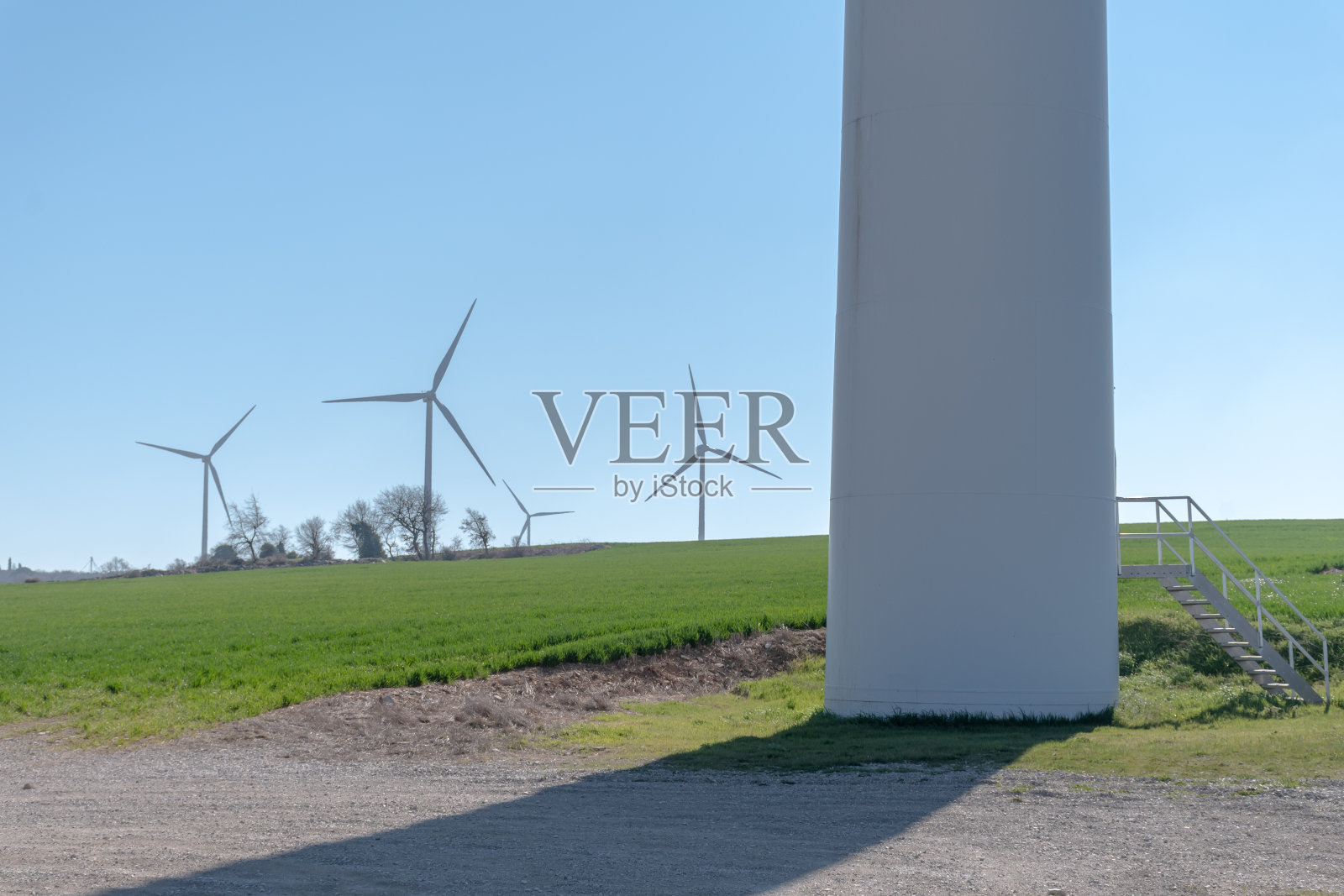 前景中的一个风力涡轮机基地和背景中的风力涡轮机在田野的中间照片摄影图片