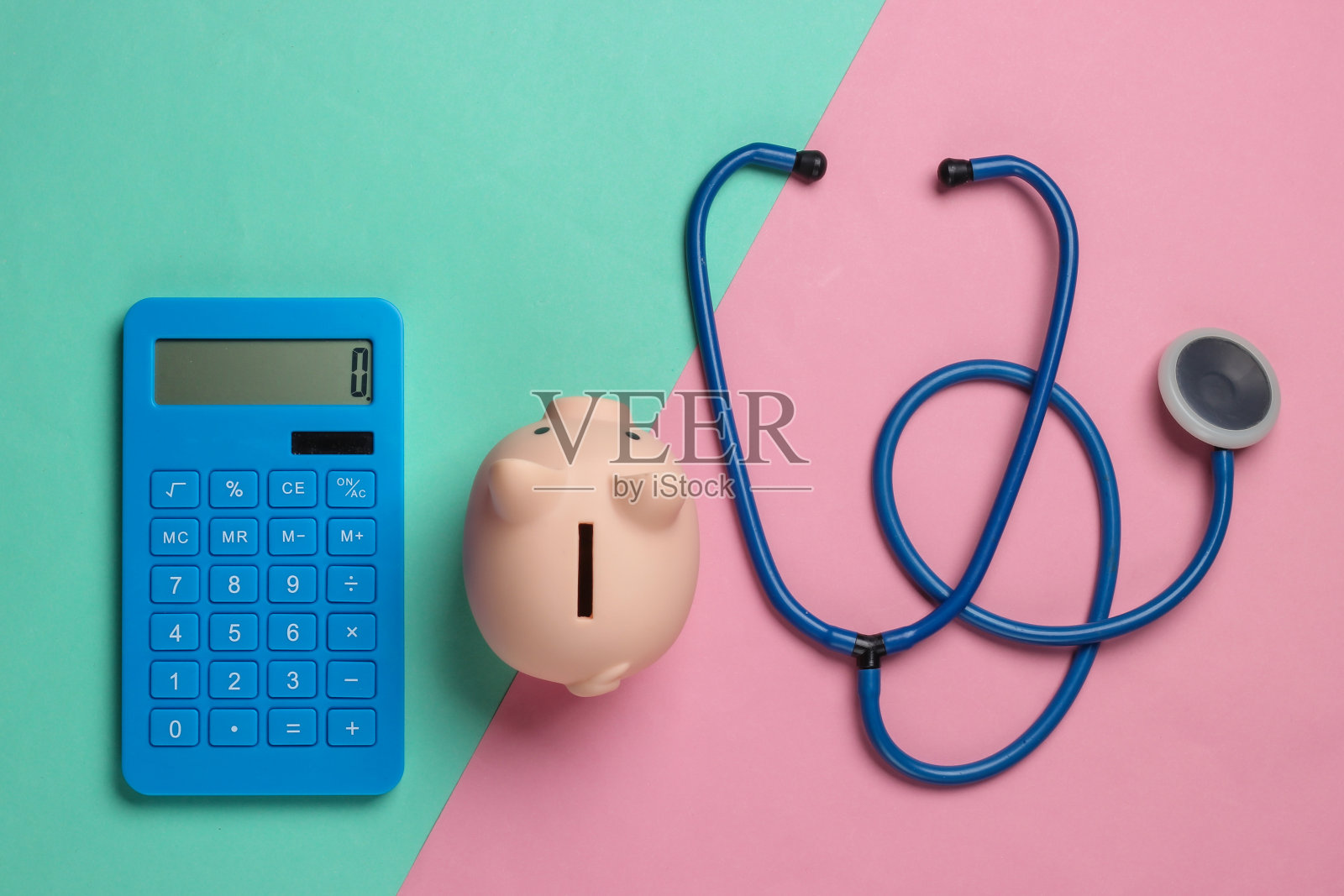 医药费用。带听诊器的储蓄罐，粉蓝色背景的计算器。俯视图照片摄影图片