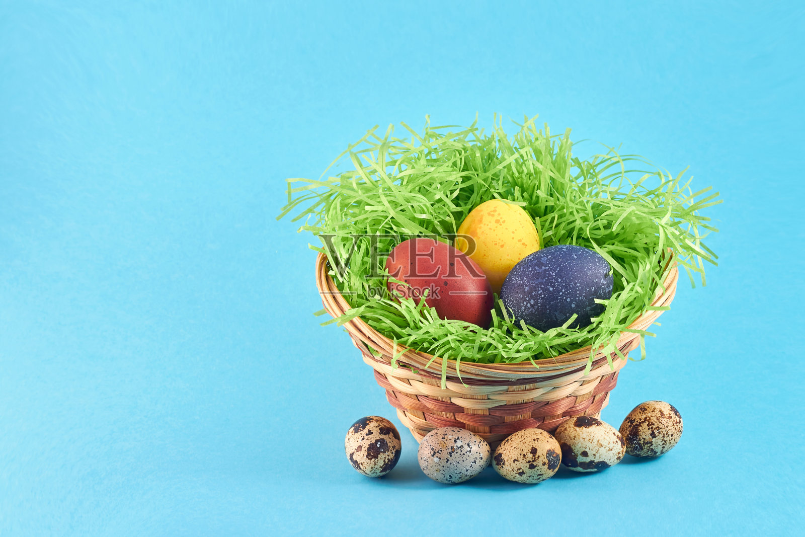 蓝色背景的篮子里装着五颜六色的复活节彩蛋。鹌鹑蛋。复活节的概念。照片摄影图片