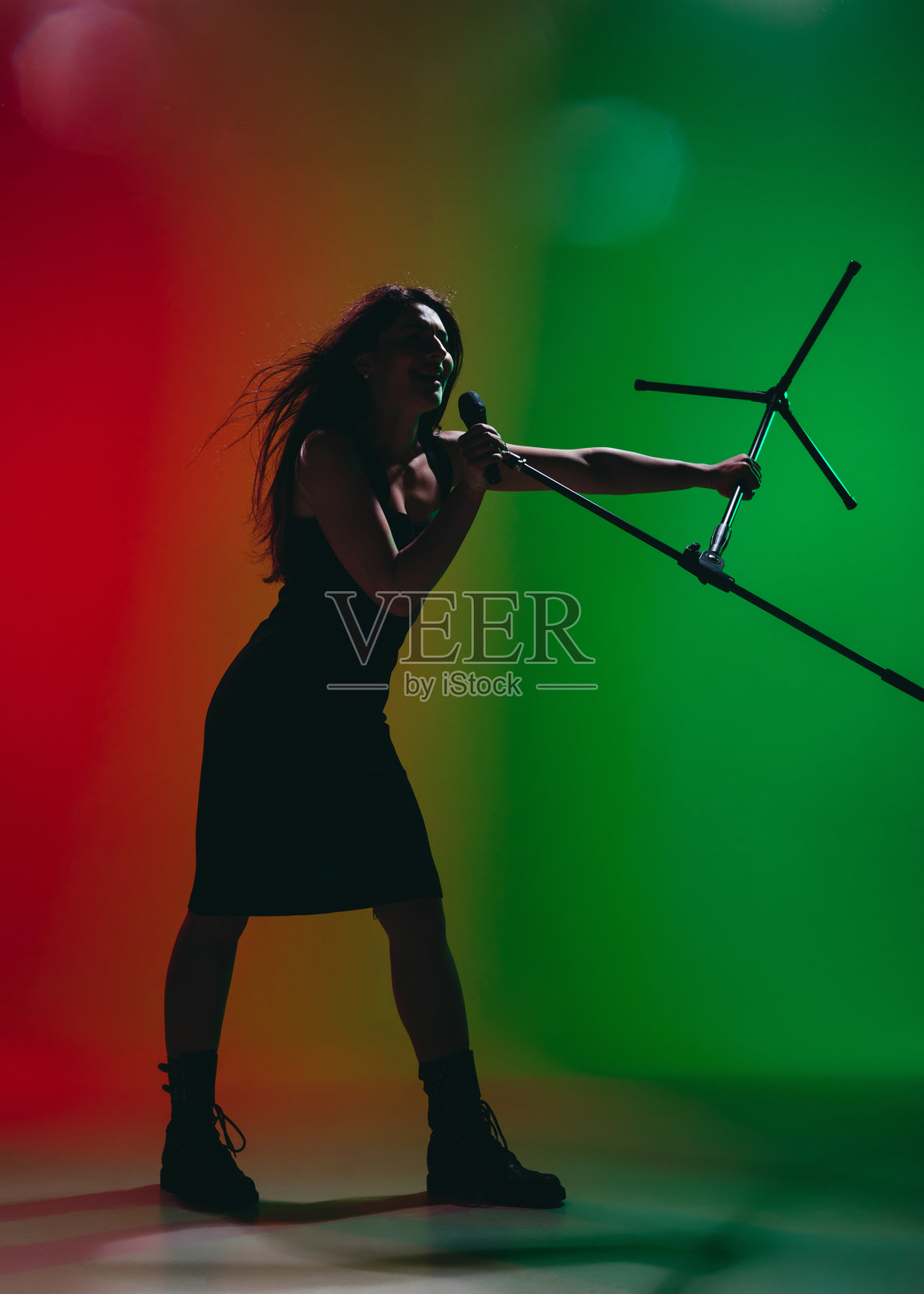 女歌手的肖像孤立在霓虹灯下的红绿背景。照片摄影图片