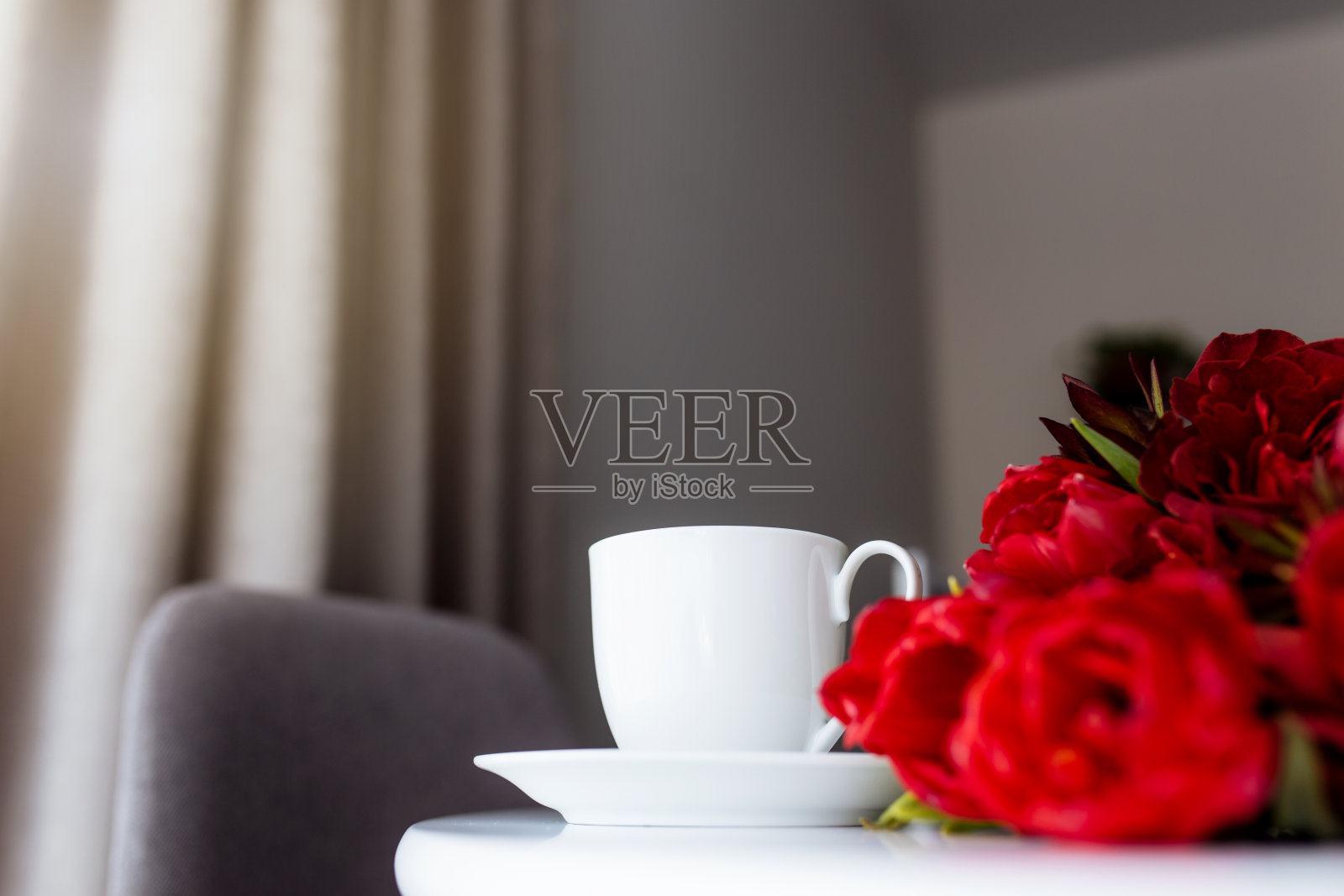 桌上放着一束红色的郁金香和白色的咖啡杯。贺卡概念照片摄影图片