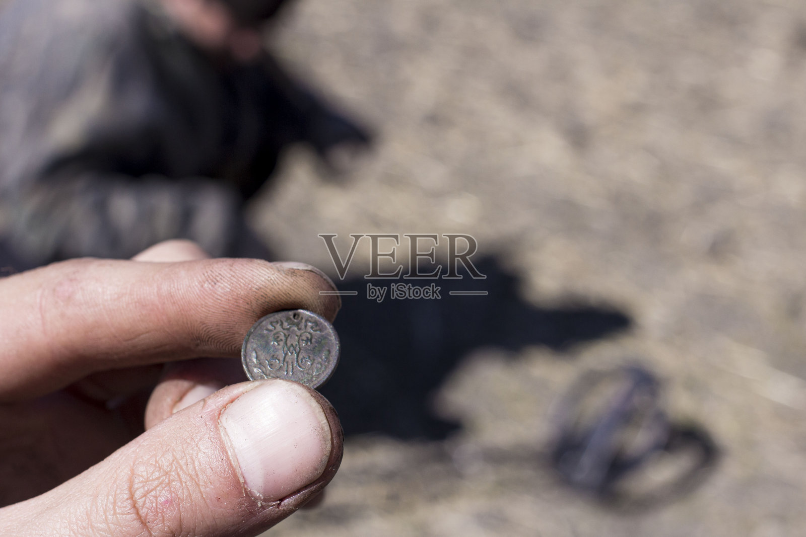 一名男子拿着金属探测器在一个古老的防御堡垒的广阔范围内寻找古代钱币和文物，前景和背景都因散景效果而模糊照片摄影图片