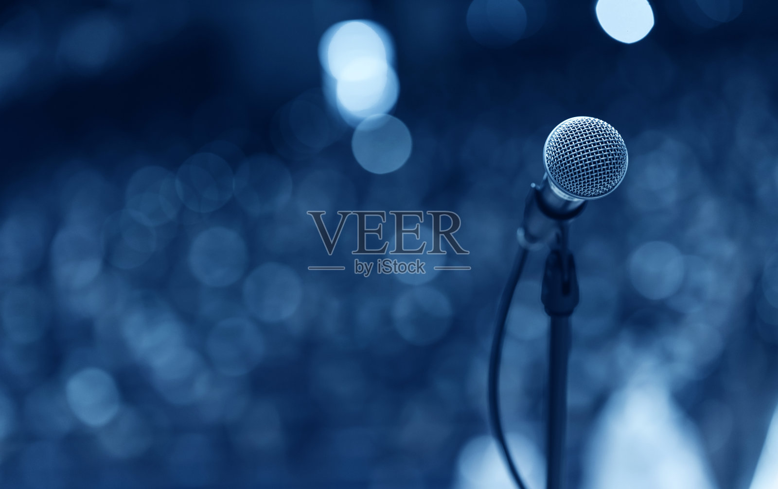 在会议室或会议厅，麦克风的特写高于抽象模糊的参与者照片摄影图片