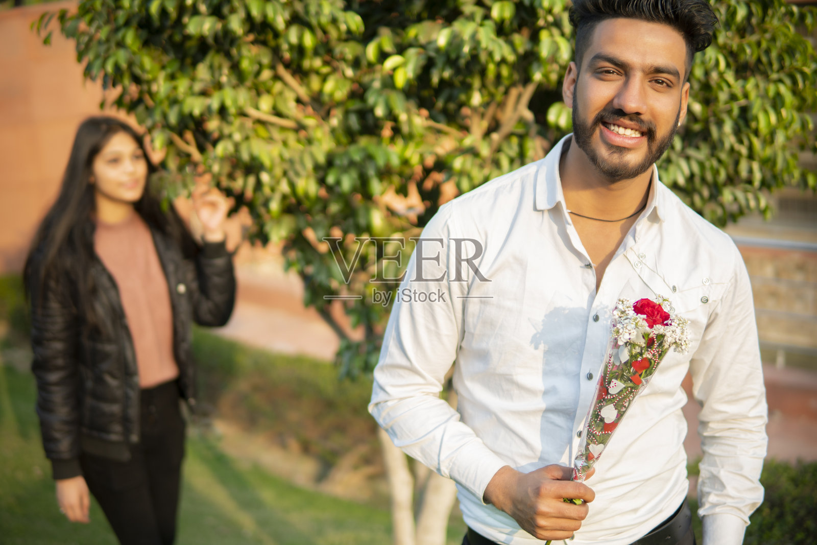 幸福的年轻人手捧红玫瑰等待着他的女朋友。照片摄影图片