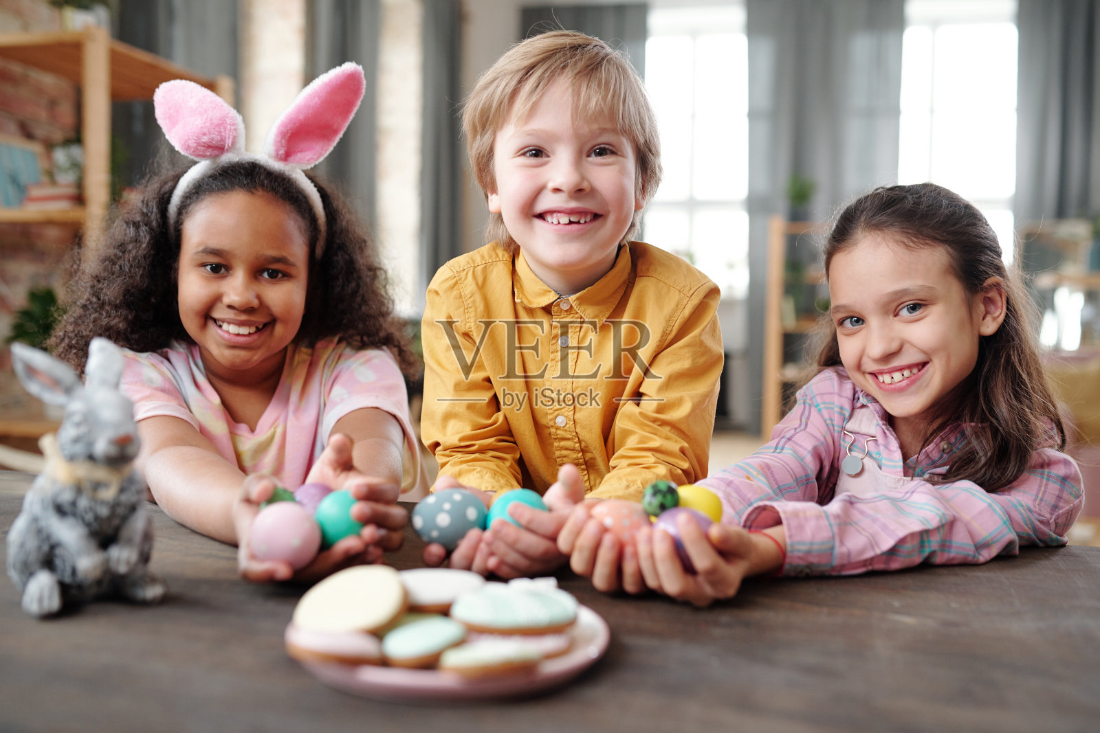 快乐的跨文化小朋友穿着休闲装拿着复活节彩蛋照片摄影图片