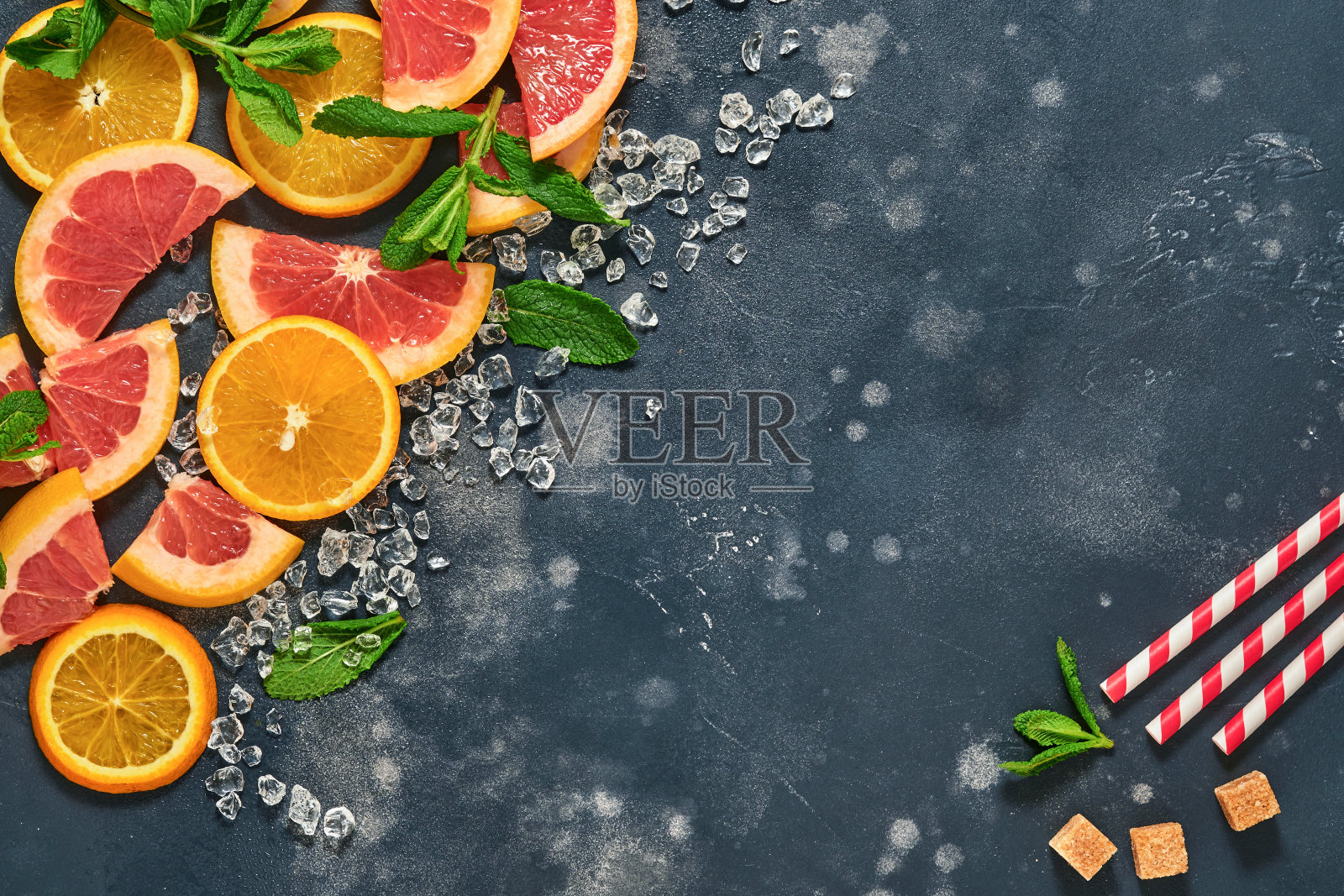 柚子和橙子片，薄荷，甘蔗糖，冰，鸡尾酒管，榨汁机或压榨黑石老背景。配料制作夏日海滩鸡尾酒背景饮品。模拟。前视图。照片摄影图片