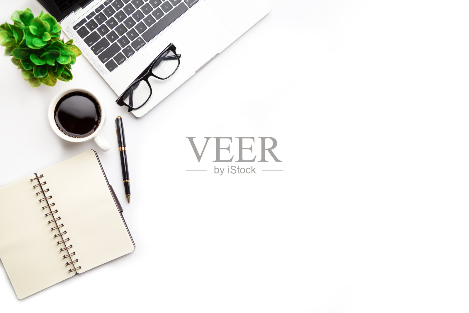 平躺，俯视图办公桌桌。工作空间，笔记本电脑，办公用品，铅笔，绿叶，和咖啡杯在白色的背景。照片摄影图片