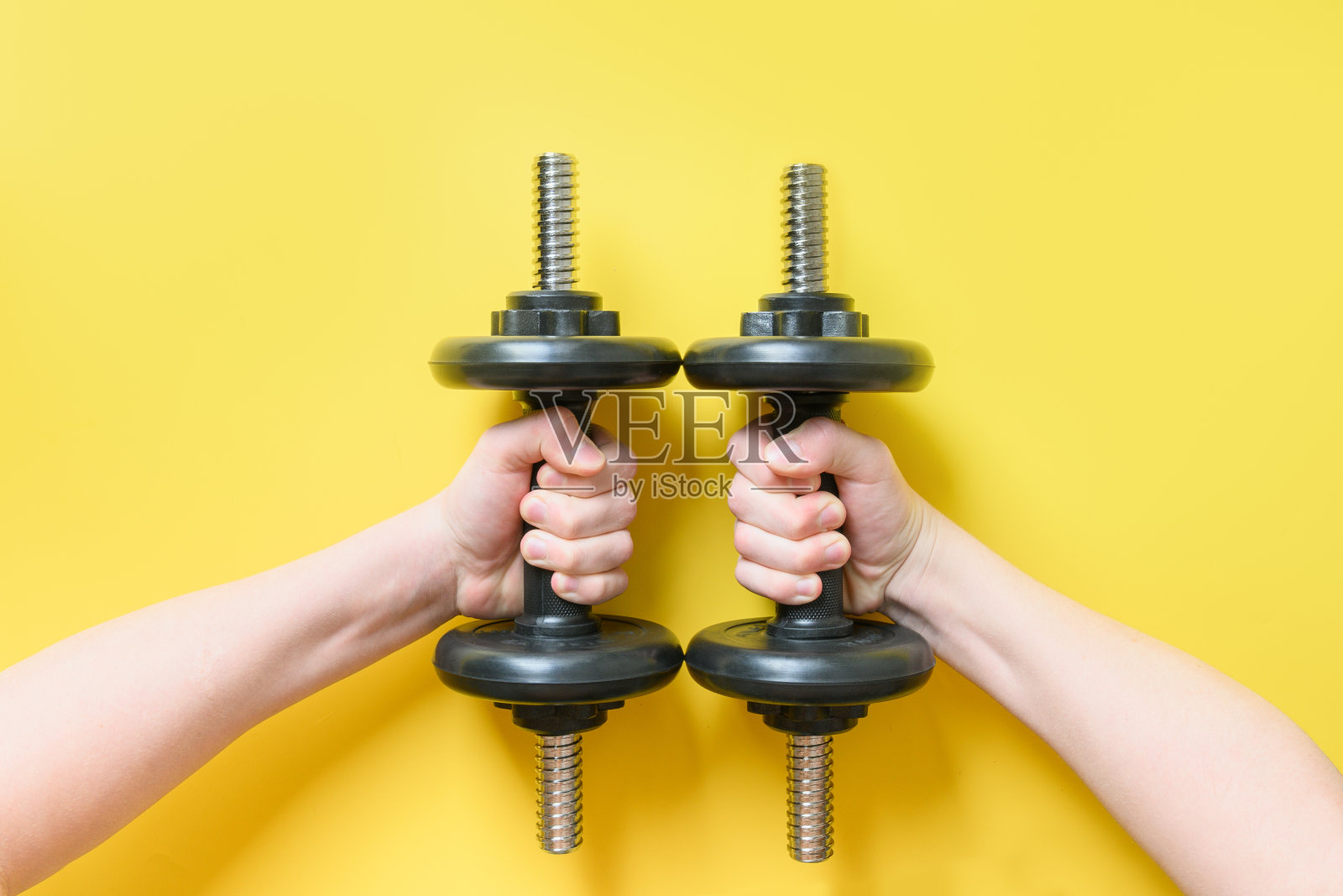 手里拿着黑色哑铃，手里拿着黄色哑铃。体育健身器材。照片摄影图片