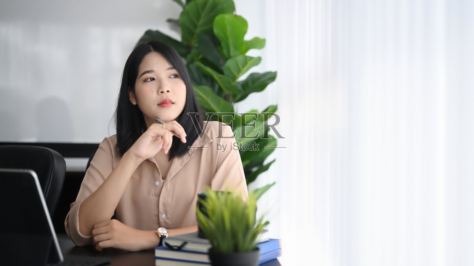 深思熟虑的女商人坐在办公室里看着窗外，想着她的工作。照片摄影图片