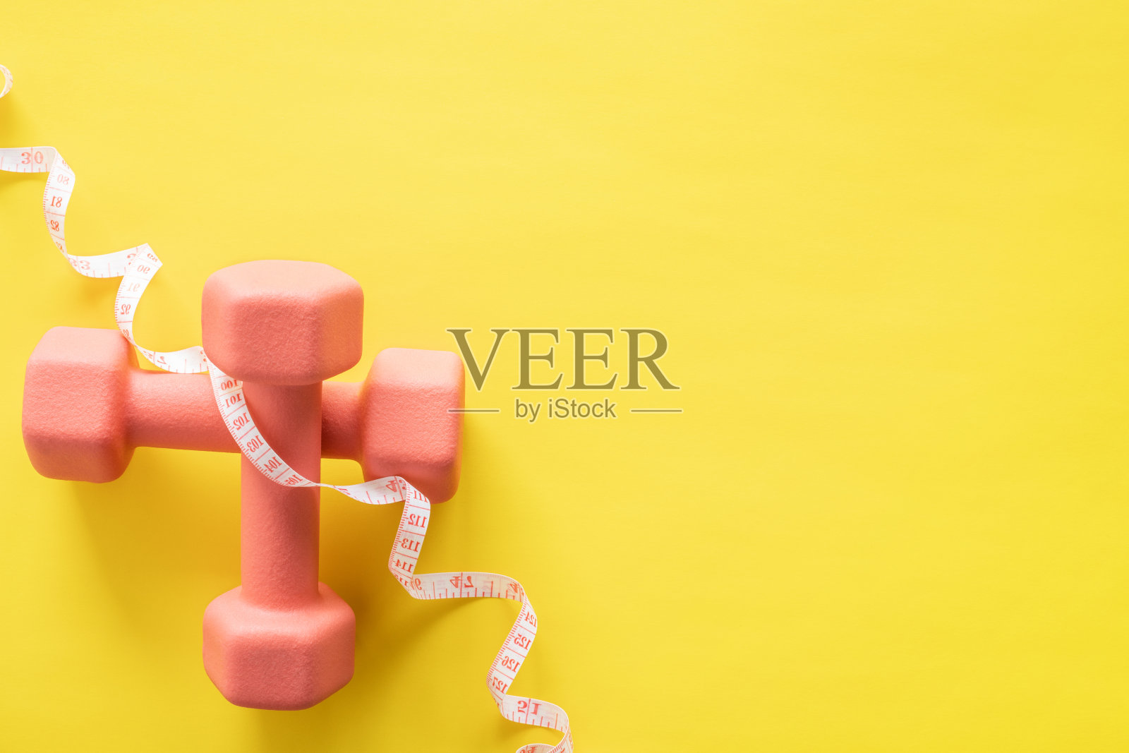 黄色背景上的哑铃和卷尺。健身、运动和锻炼照片摄影图片