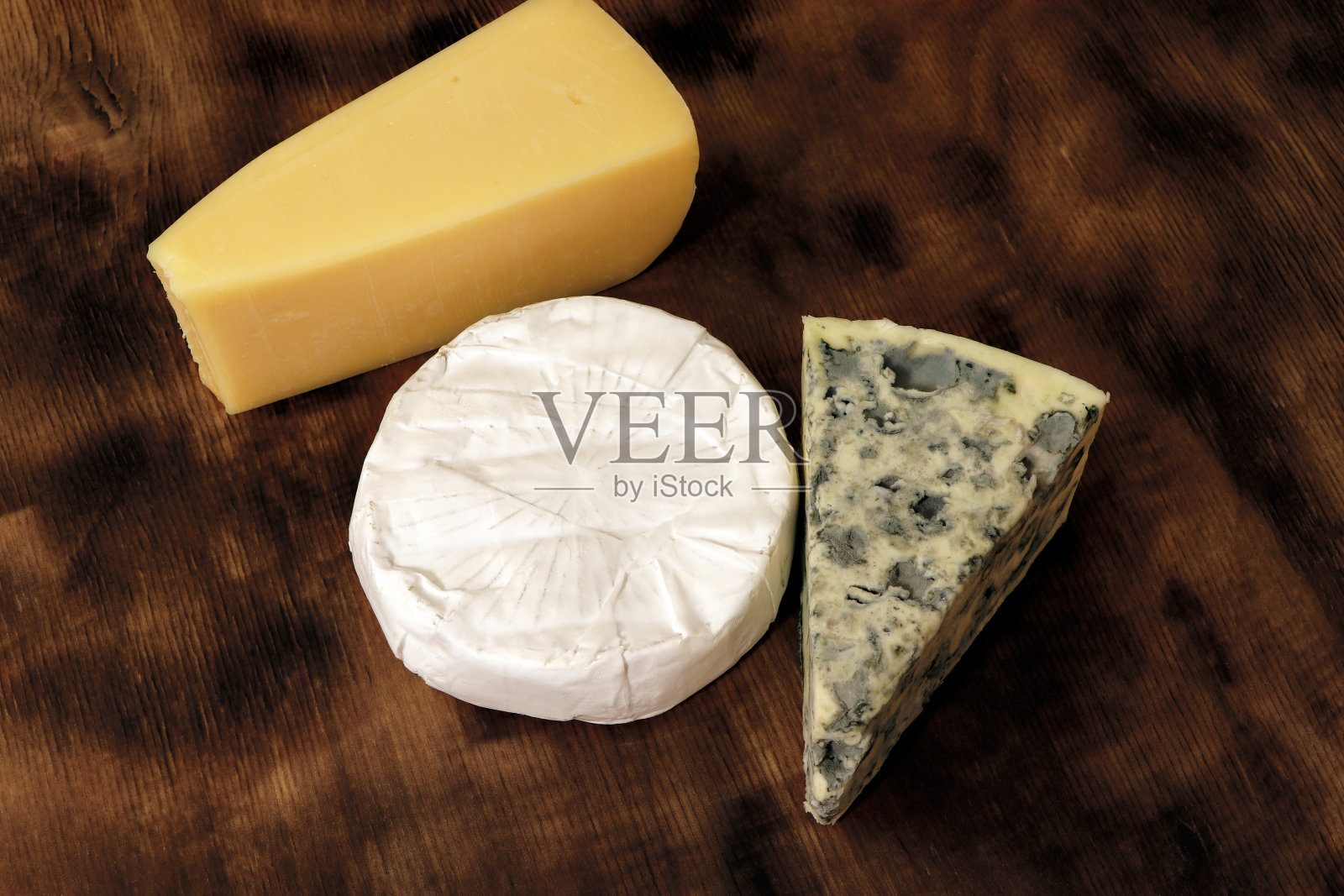 在木板上搭配不同类型的奶酪。不同的奶酪，蓝纹奶酪，发霉的奶酪，卡门贝尔奶酪和帕尔马干酪。照片摄影图片