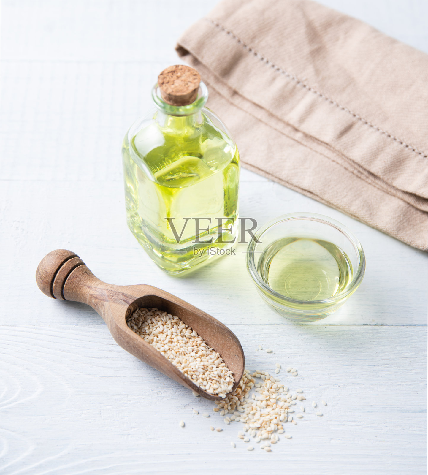 天然植物油从芝麻种子在一个透明的瓶子在木制背景。饮食健康的食物照片摄影图片