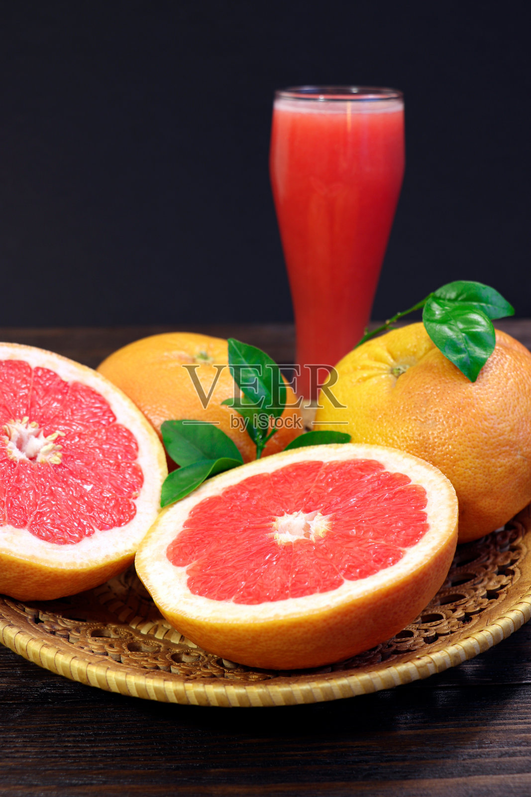 木桌上放着一杯新鲜的葡萄柚汁和葡萄柚水果。健康食品。照片摄影图片