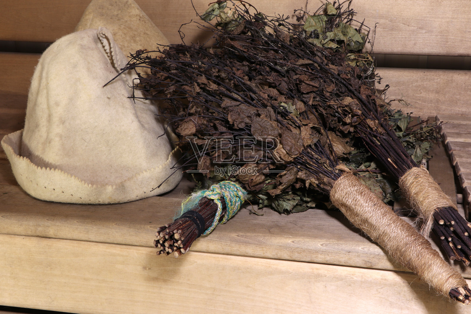 木制背景上的桦木扫帚和桑拿帽。照片摄影图片