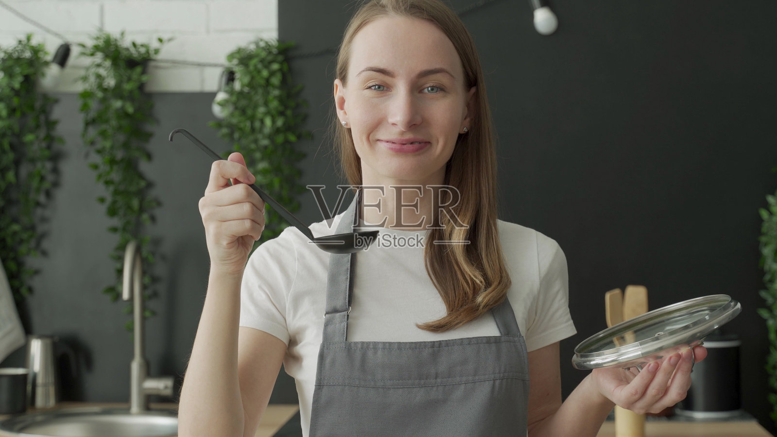 快乐的女人用勺子喝汤，微笑着在厨房里照片摄影图片