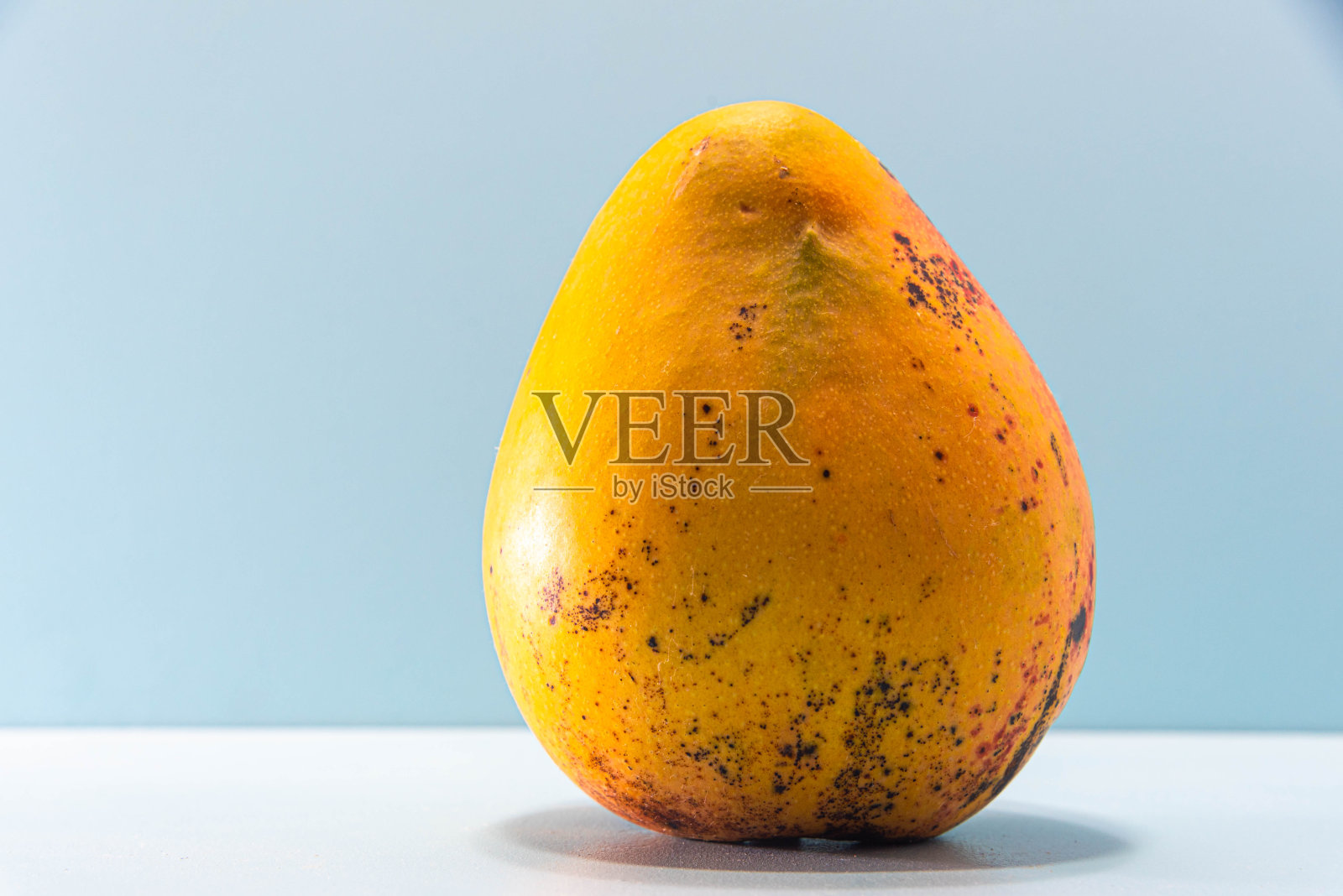 新鲜的粉红色芒果水果在蓝色的背景。水果富含纤维和蛋白质照片摄影图片