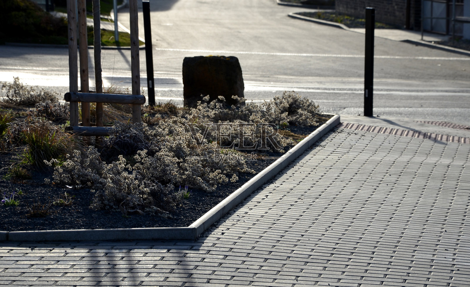 村里的新景观。街道花坛新栽了多年生植物。覆盖着灰色的砾石。有一个饮水机和大石头保护植物免受交通照片摄影图片