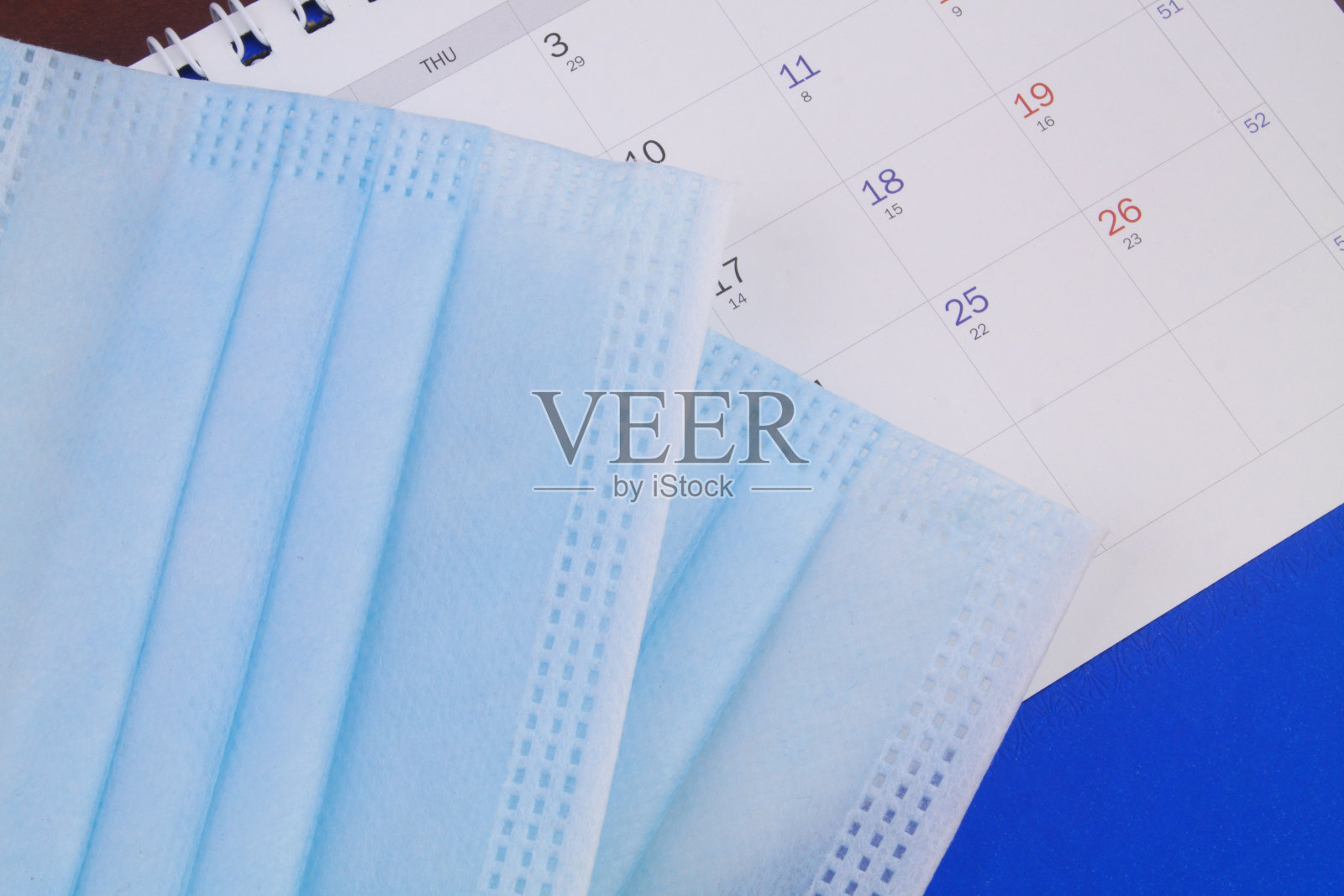 日历背景上的防护医用口罩。照片摄影图片