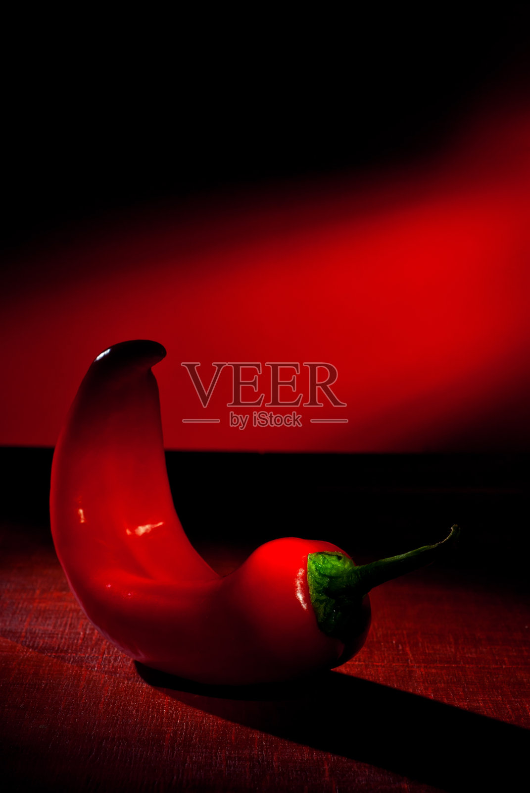 辣椒靠近了。木板上放智利辣椒。红色背景上的蔬菜。作为一种艺术效果来对比戏剧性的光线。照片摄影图片