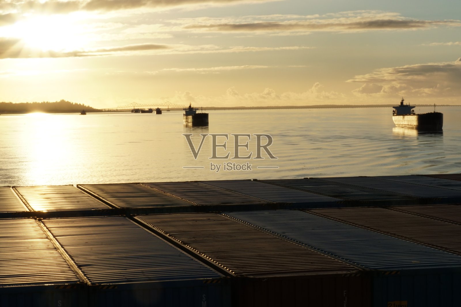 从集装箱船上的其他商船停泊在哥伦比亚河入口附近，从太平洋那里是位于波特兰港口在日落。照片摄影图片