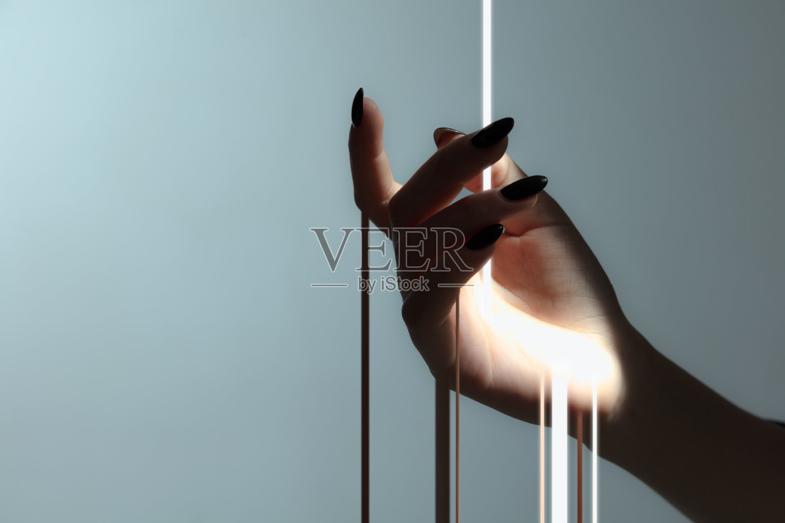 光线通过精致的女性手孤立在灰色背景。照片摄影图片