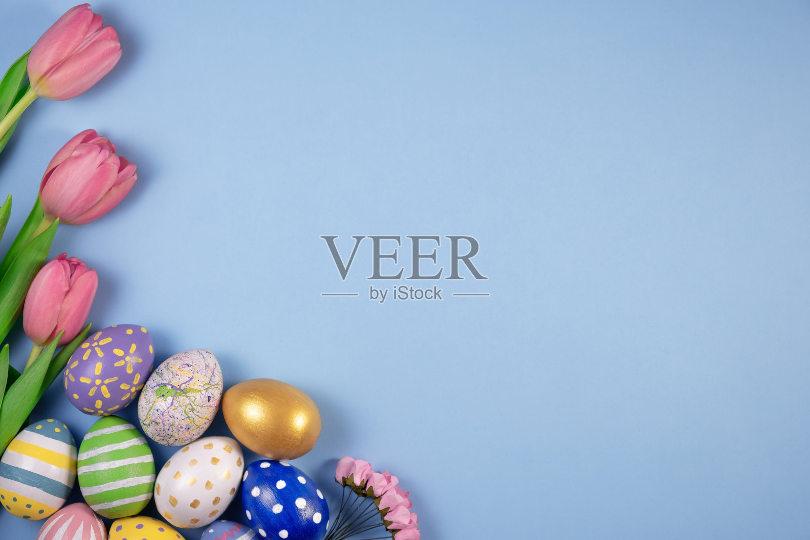 粉红色的郁金香花和五颜六色的鸡蛋在蓝色的背景上。复活节快乐卡片。等待着春天照片摄影图片